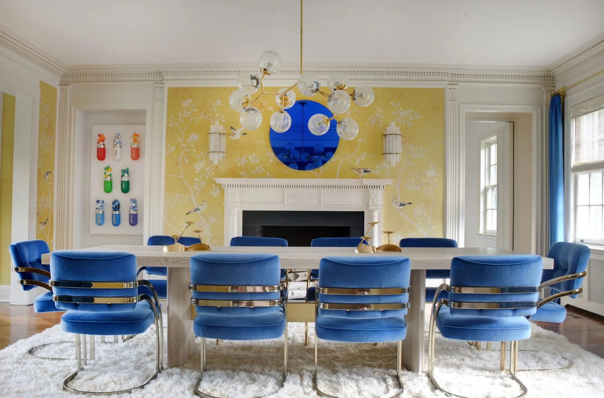Dining room with deep blue chairs, vibrant yellow walls, and bold, playful decor by Good Bones Design