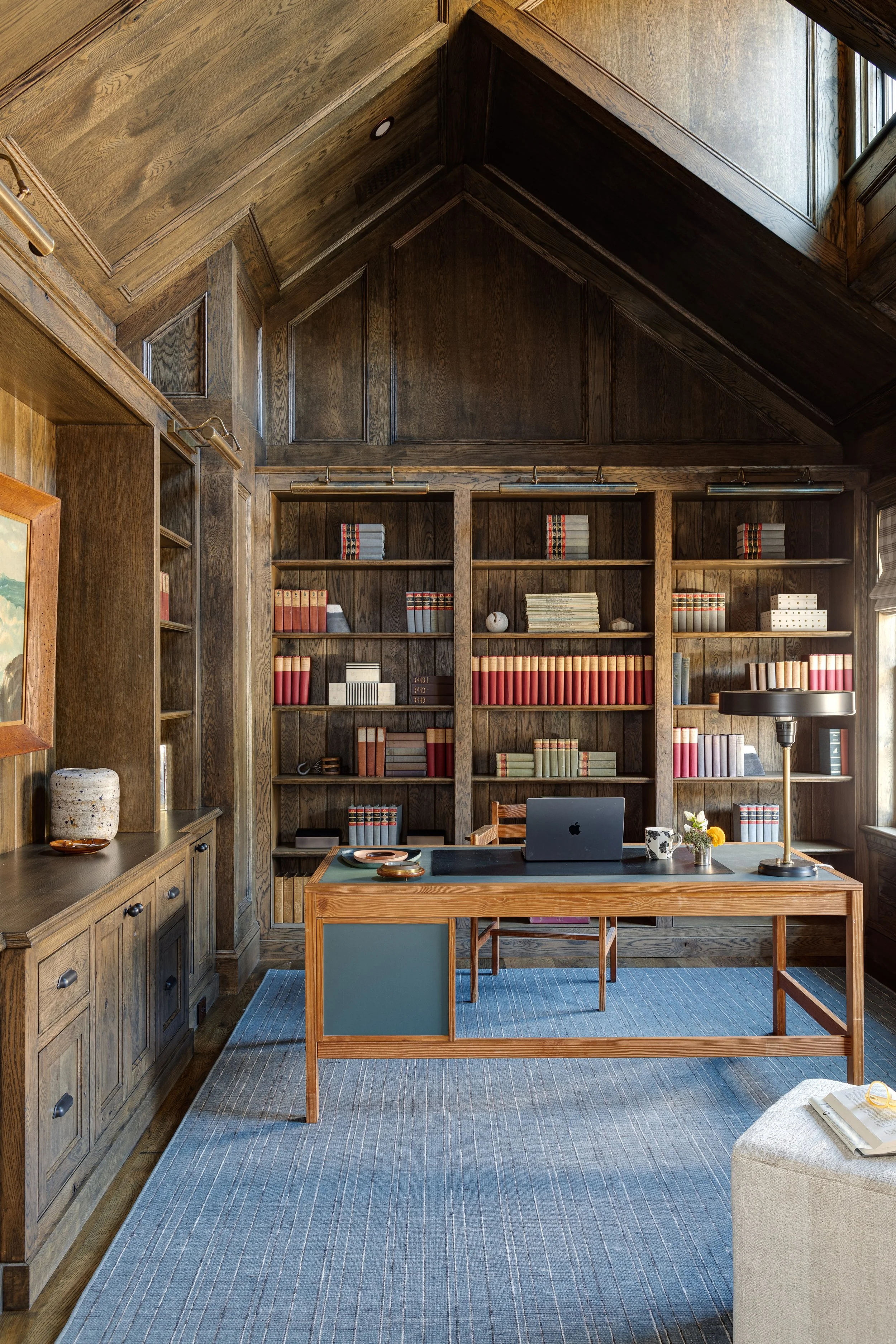 Cozy and masculine office interior by Good Bones Design with wood accents, blue rug and styled bookshelves