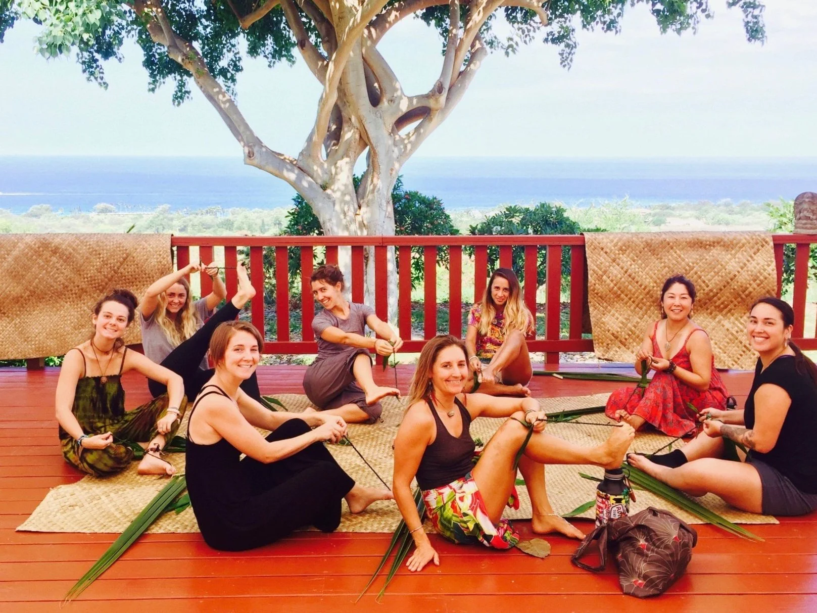 Participants making leaf leis together on the ocean-view yoga deck.