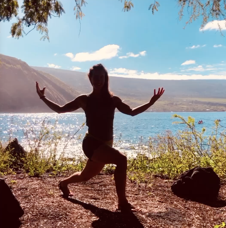 Silhouette of a yoga practitioner overlooking a coastal bay.