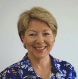 A smiling woman with short blonde hair wearing a blue patterned blouse