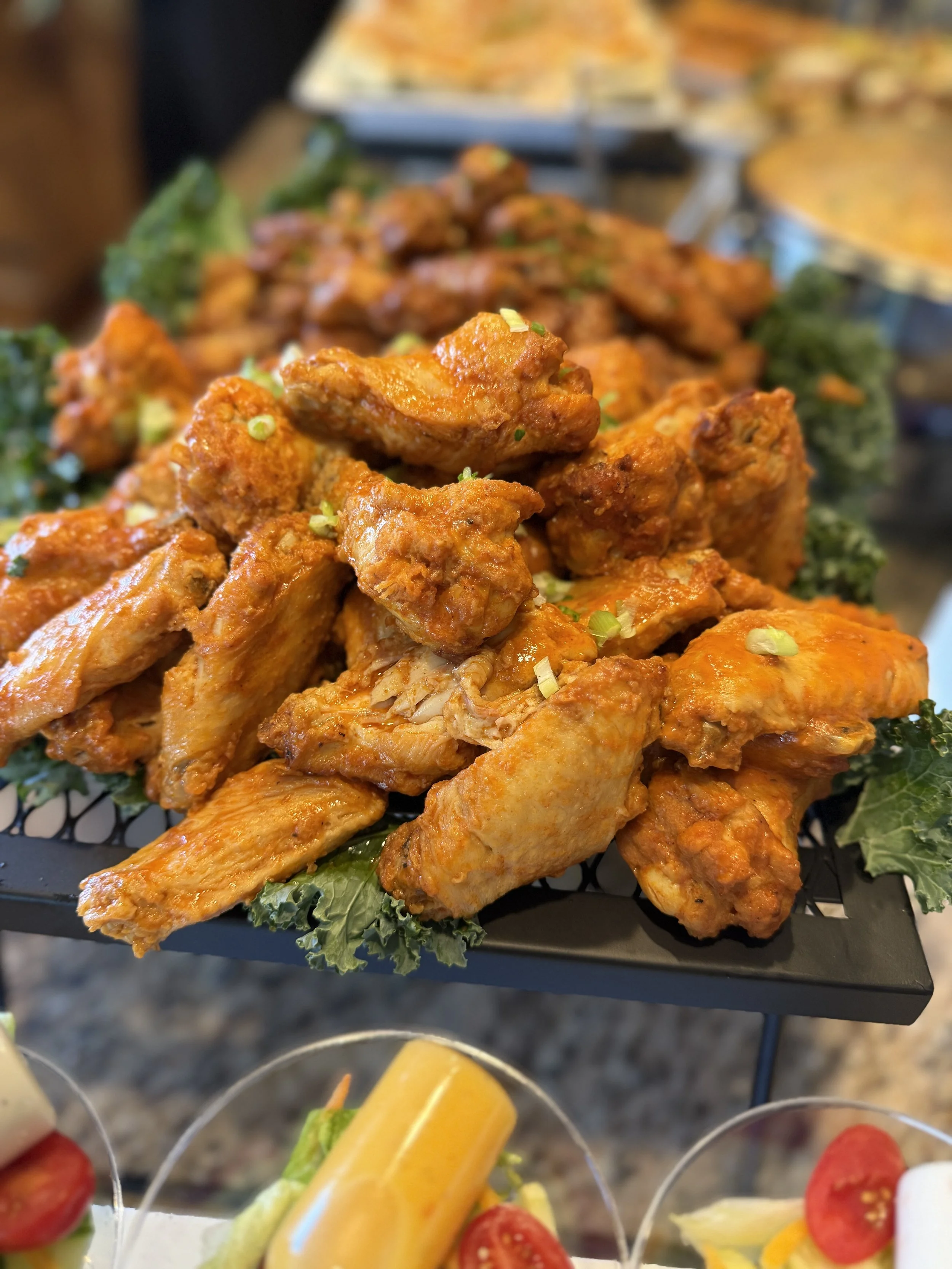 Basket of buffalo chicken wings garnished with chopped green onions, served on lettuce leaves.