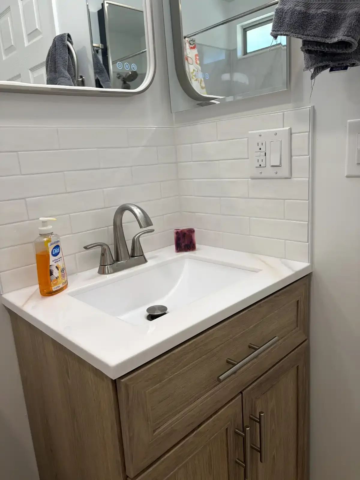 Bathroom vanity with wood-grain cabinet, white countertop and subway tile backsplash in Redding
