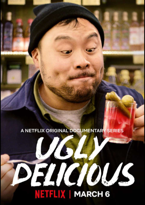 A man with a black beanie and dark jacket holding a glass of green olives and pickle, looking at it with a content expression. Behind him are shelves with bottles. Text on image promotes a Netflix documentary series titled "Ugly Delicious," premiering on March 6.
