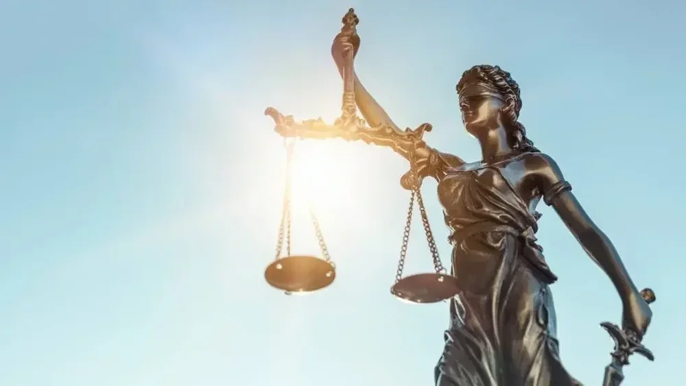 Statue of Lady Justice holding the scales against a blue sky