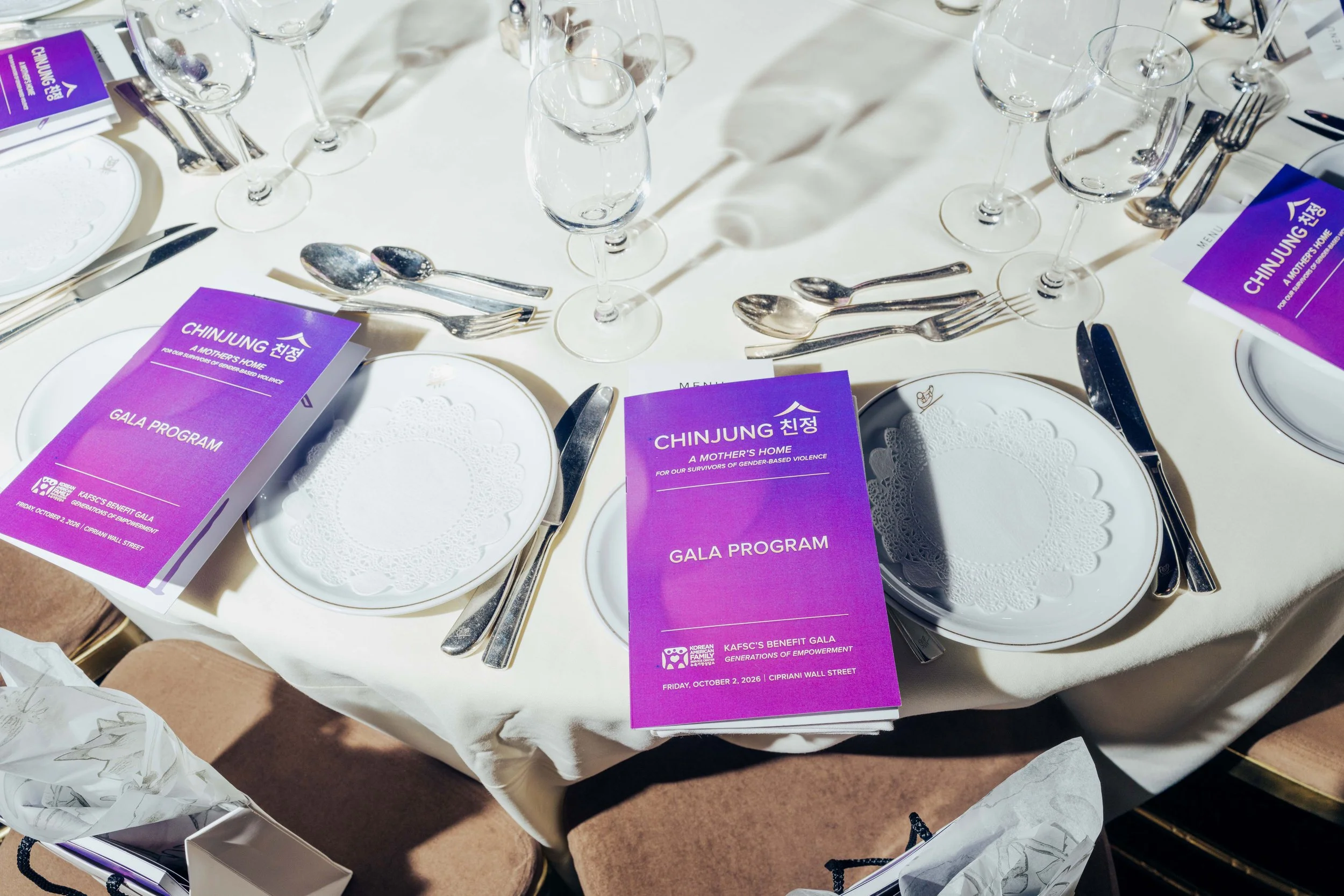 Elegant banquet table setting featuring a purple Gala Program booklet alongside fine china and glassware.
