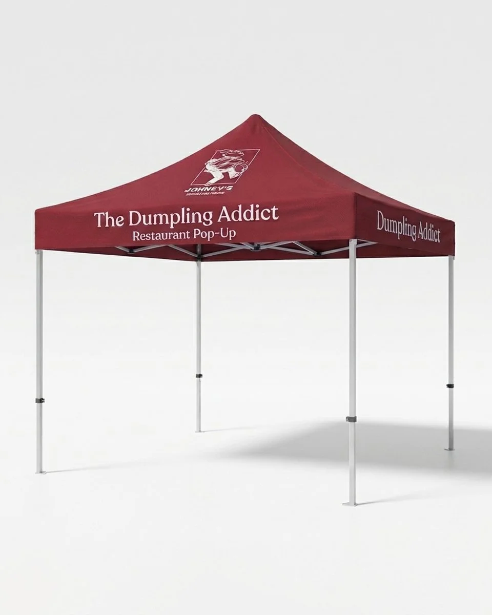 Burgundy restaurant pop-up event tent labeled “The Dumpling Addict,” with four metal legs and a dumpling-themed logo.