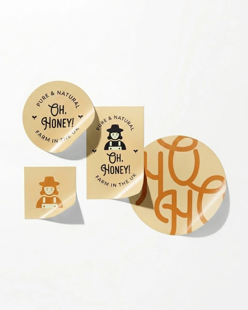Branded honey packaging and stickers reading “Oh, Honey! Pure & Natural, Farm in the UK,” featuring a beekeeper illustration.