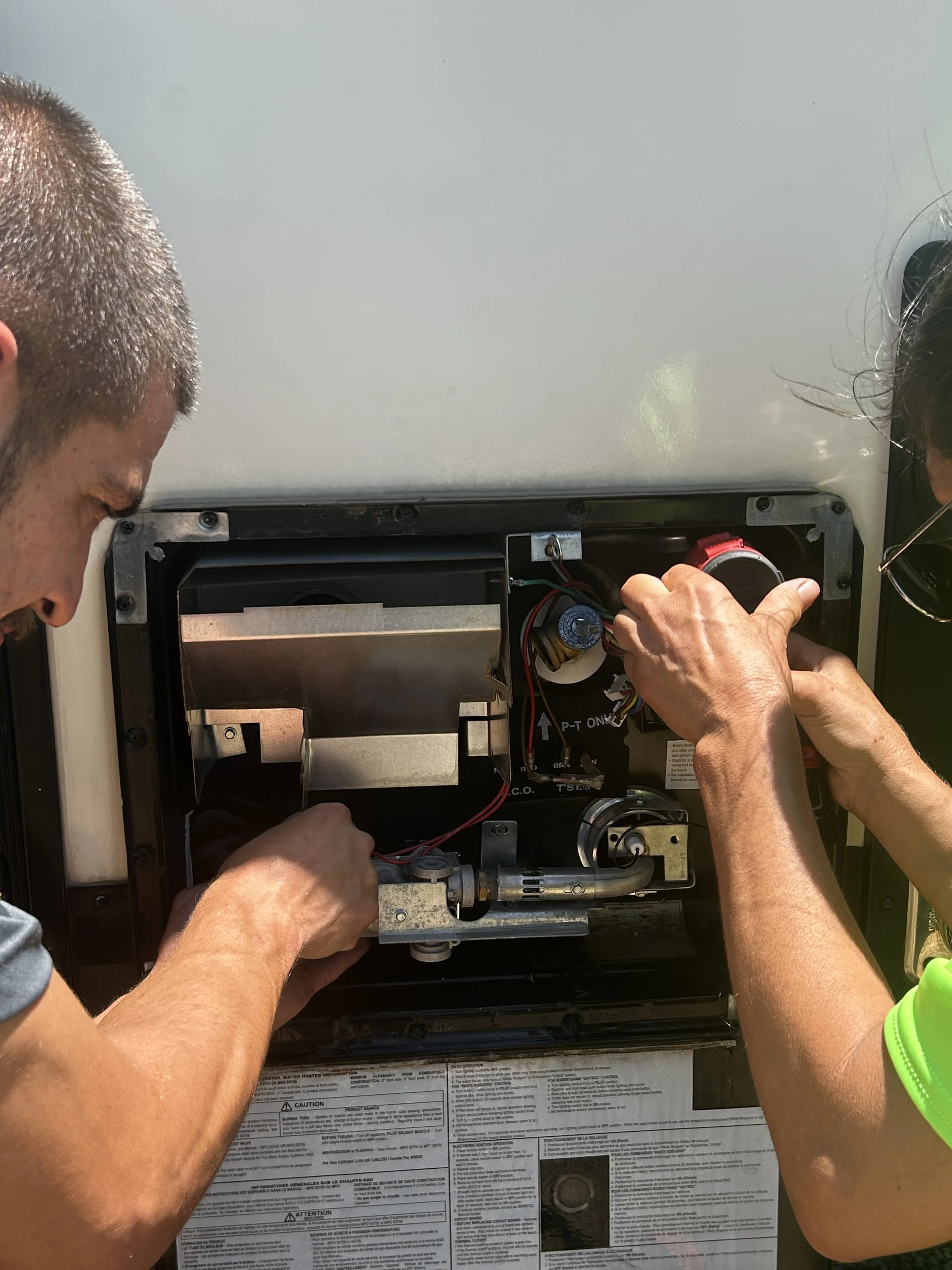 Two people working on the internal components of an industrial machine or food truck generator, inspecting and repairing inside.
