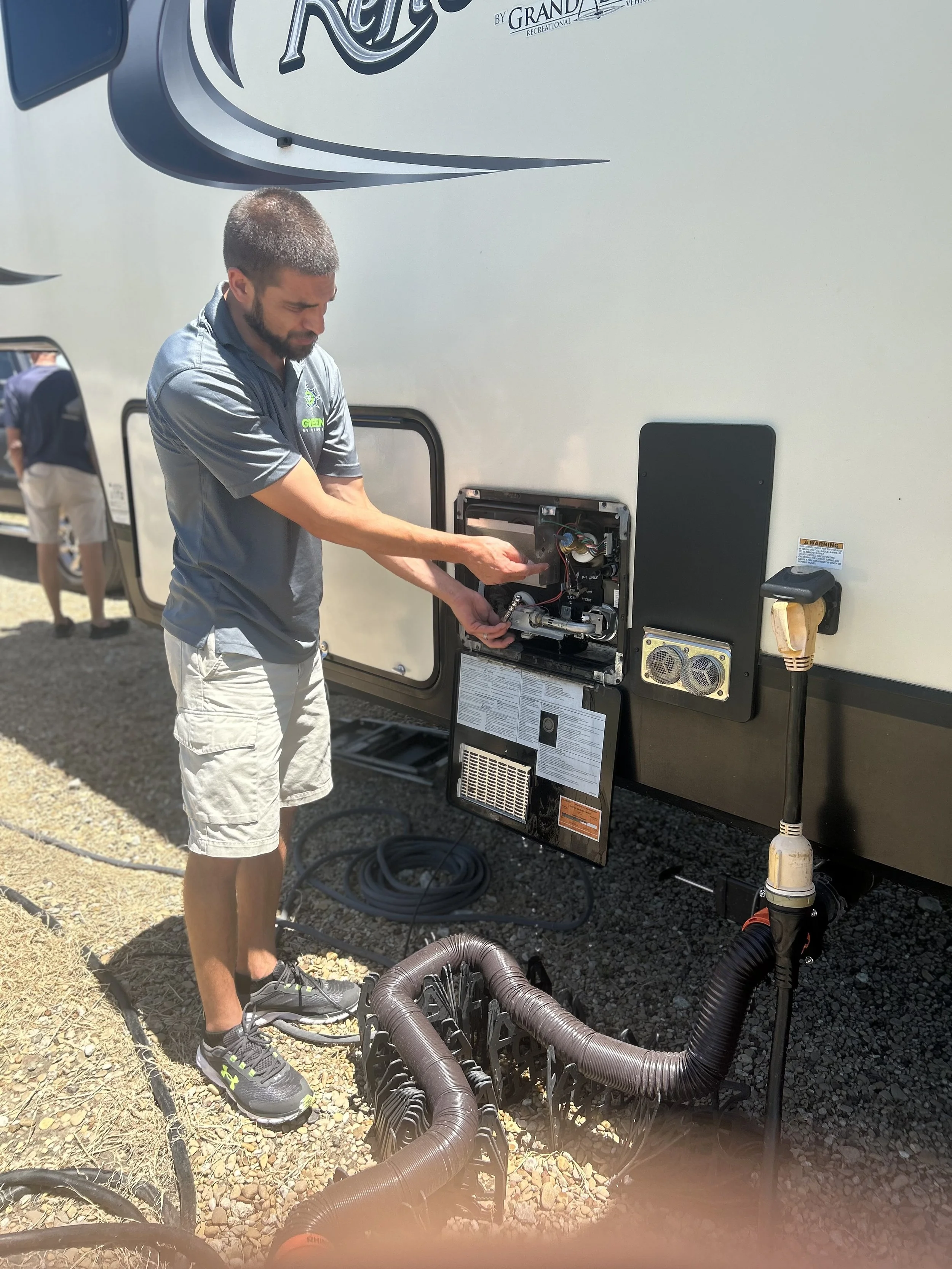 Man repairing the electrical system of a recreational vehicle (RV) outdoors on a sunny day.