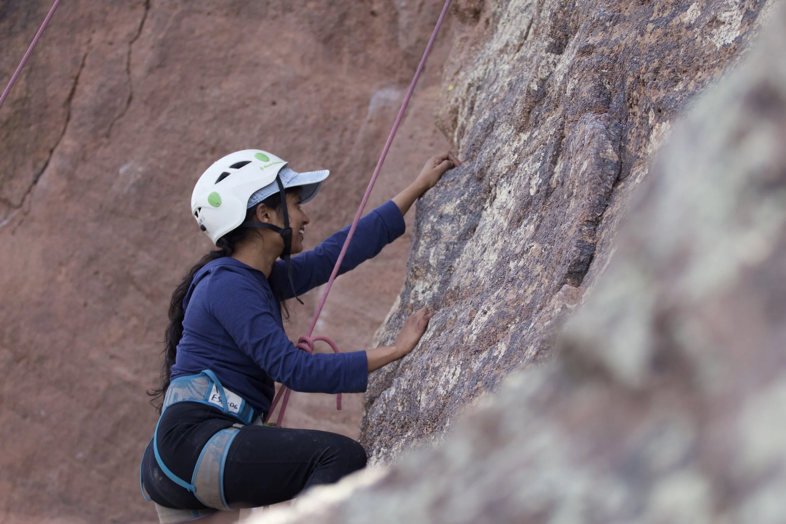 "Grit"
A person wearing a helmet and climbing gear rock climbing on a rough rock face while holding onto a rope.