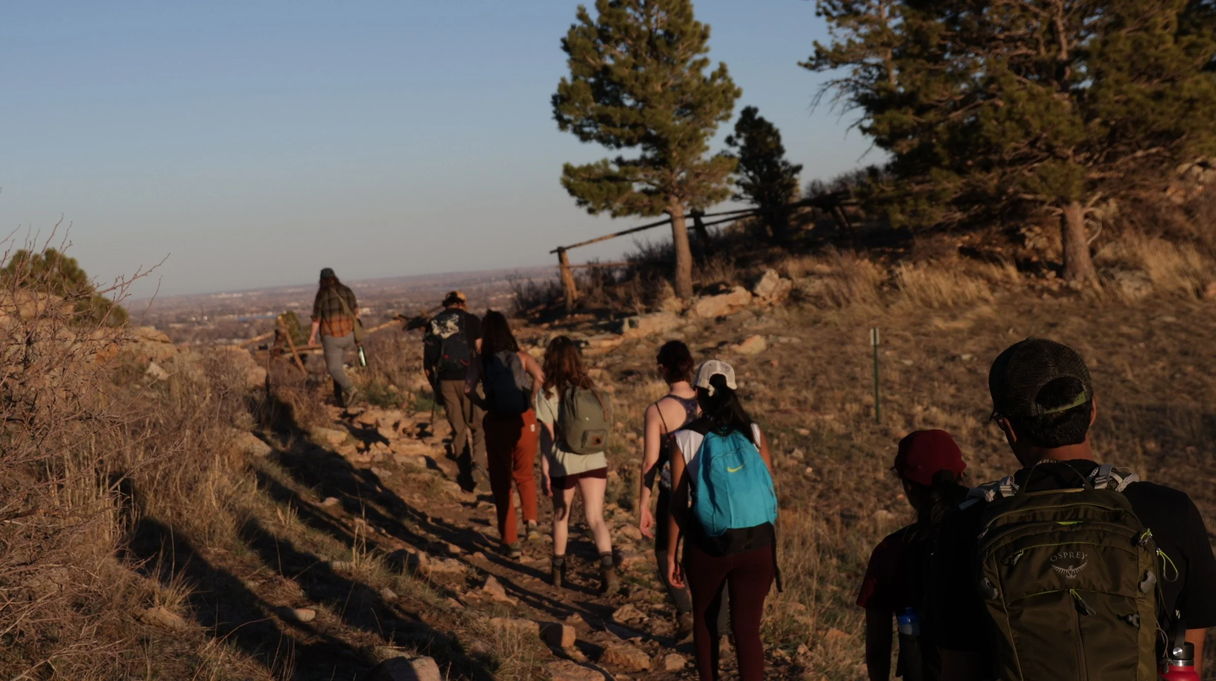 "Adventure Awaits"
Group of people hiking on a rocky trail surrounded by trees and dry grass during the day.