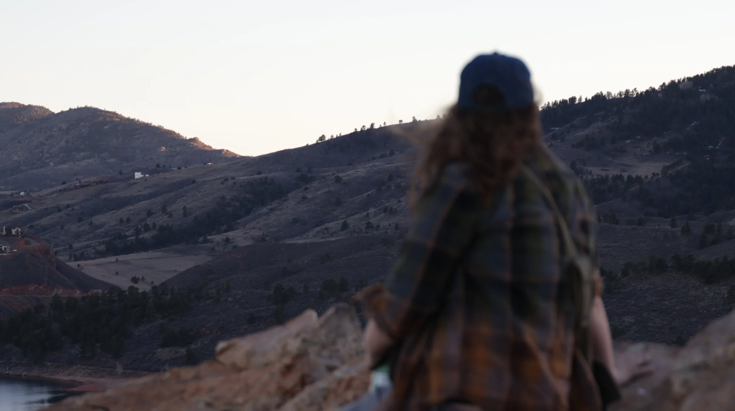 "Reflection on Horsetooth"
Person wearing a cap and plaid shirt, sitting on a rock, facing a mountainous landscape during dusk.