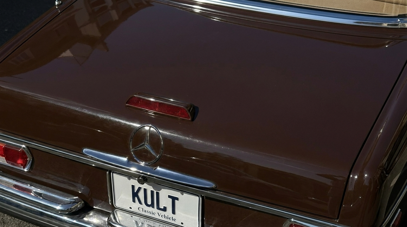 The back of a vintage brown Mercedes-Benz car with a custom license plate that says 'KULT'.
