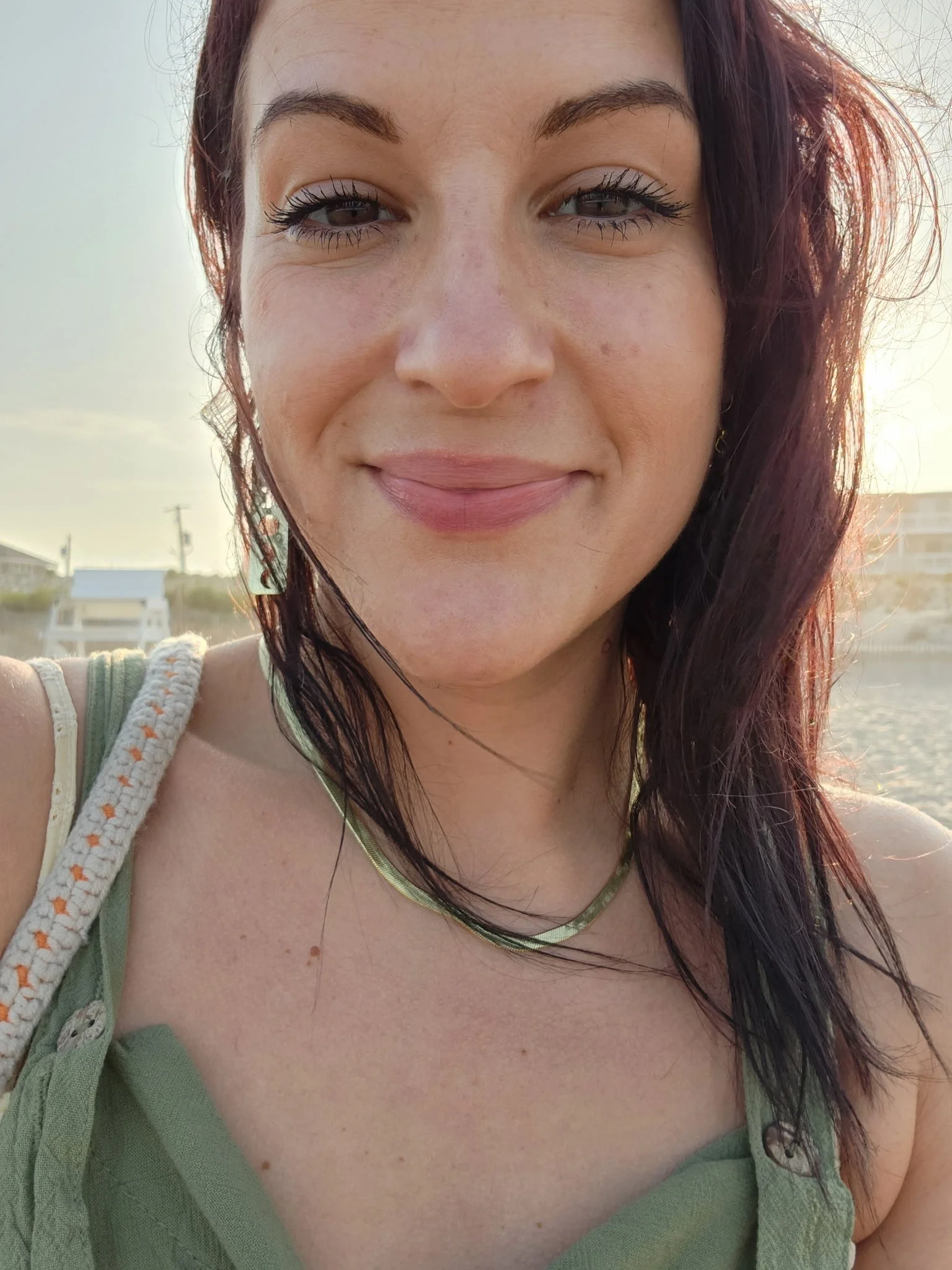 Headshot of Amie gentile smiling on the beach wearing a gold necklace and a green tank top.
