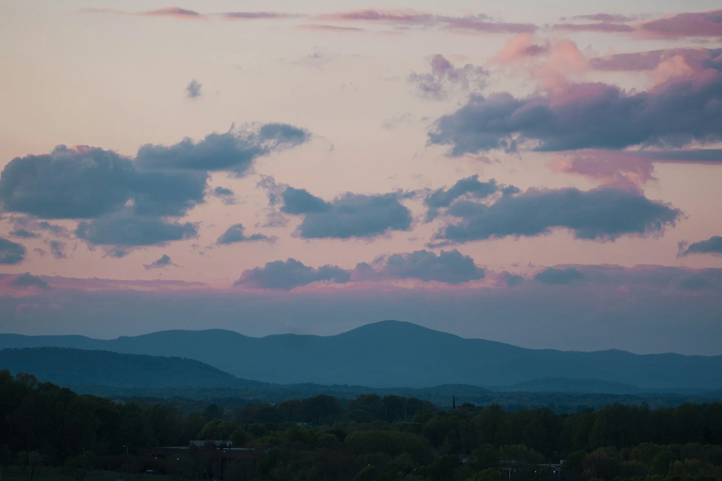 A landscape view of distant mountains under a sky with pink and purple clouds at dusk or dawn.
