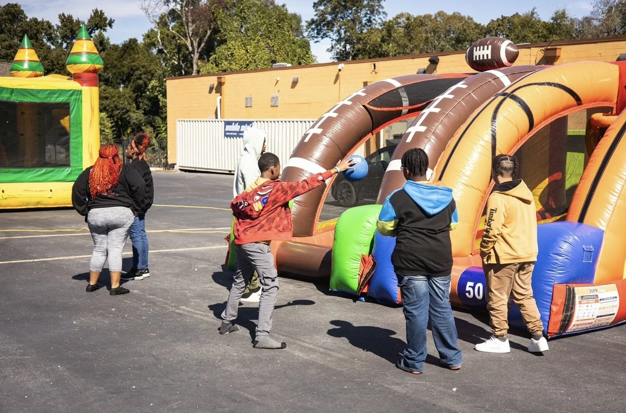 Children playing with inflatable sports games at an outdoor event.