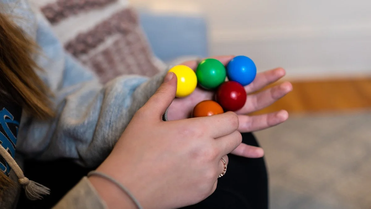 Person holding colorful balls in their hands.