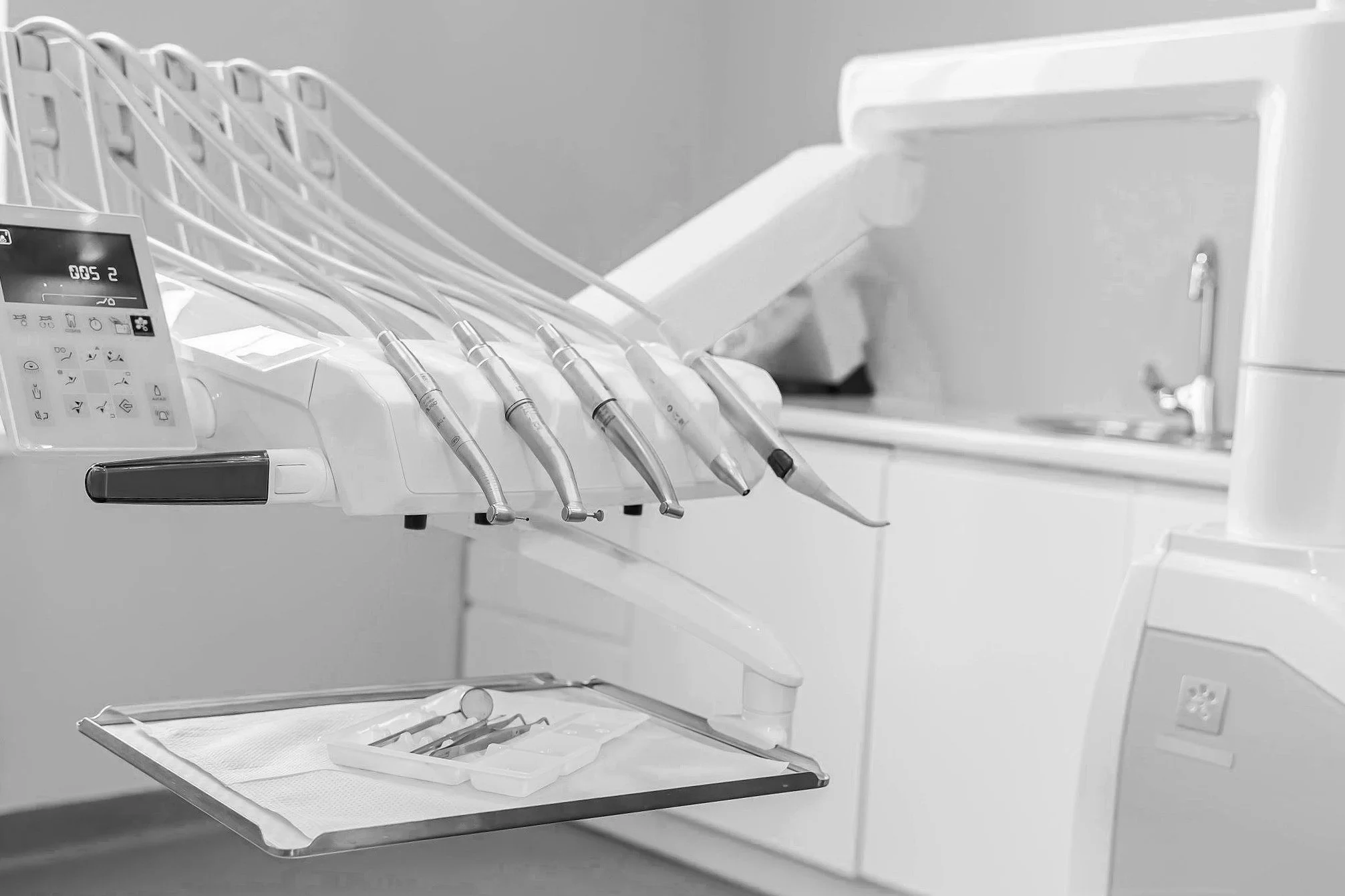 Dental equipment with handpieces and dental tools on a tray in a dental office.