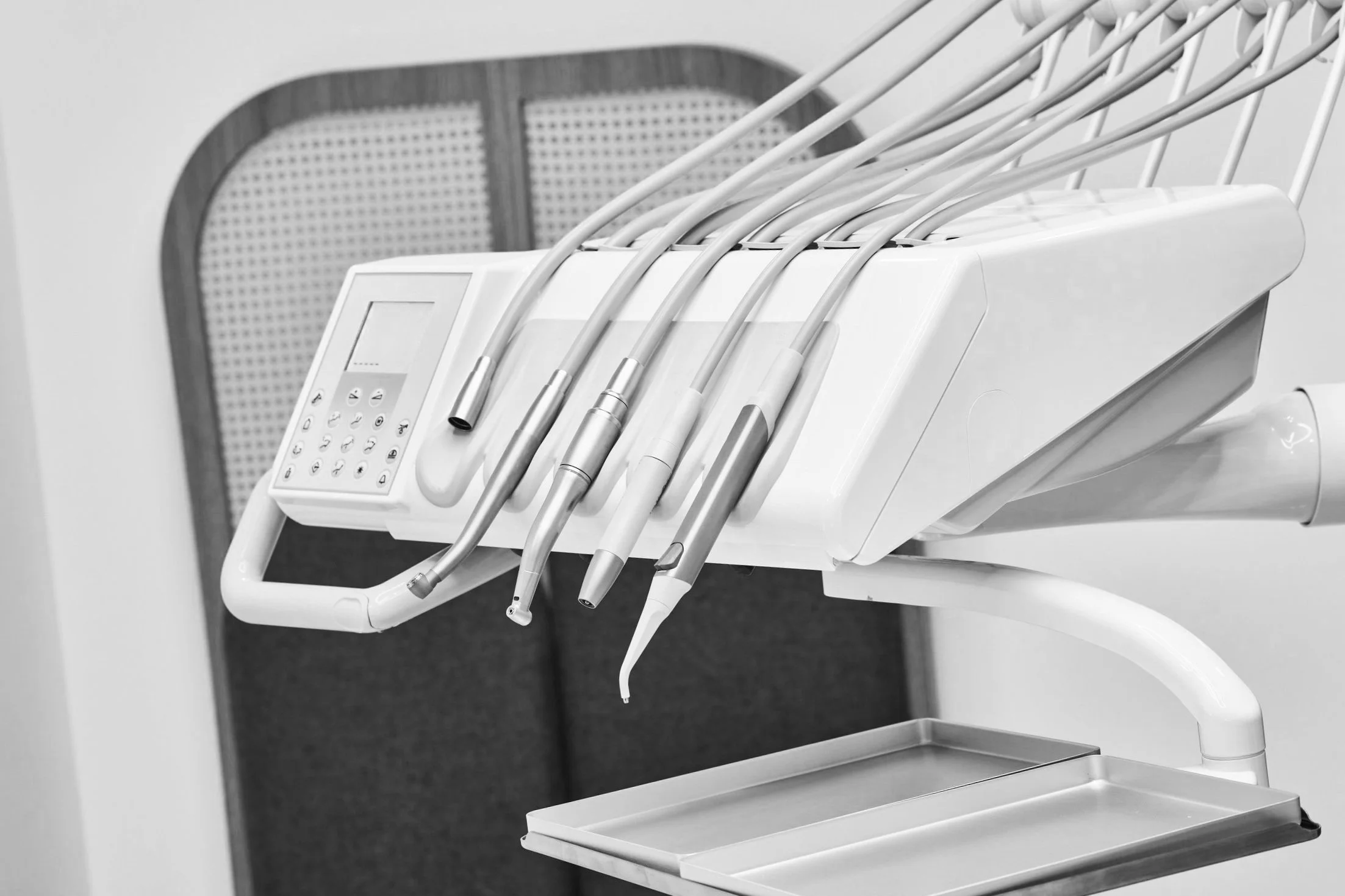 Dental equipment with various dental tools and a control panel on a mobile tray in a dental office.