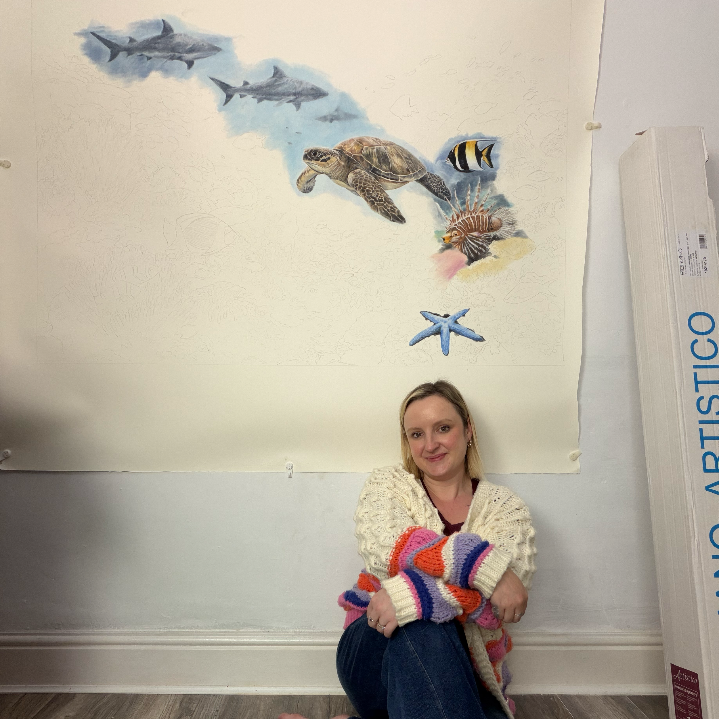 fine artist with a mural of sharks, a sea turtle, a fish, and a starfish 