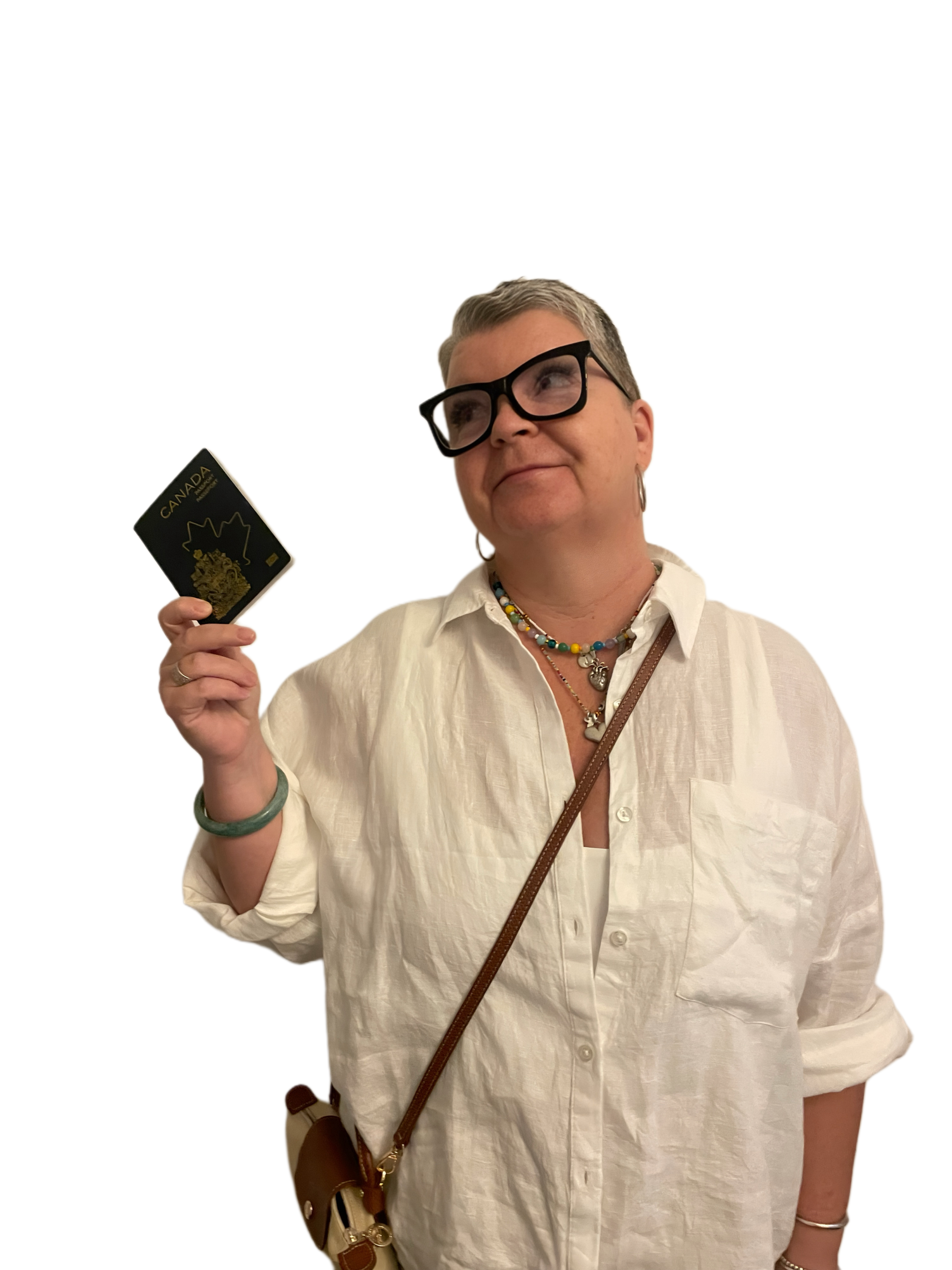 A woman with short gray hair, black glasses, wearing a white button-up shirt, colorful necklaces, a green bracelet, and a crossbody bag, holding a Canadian passport.