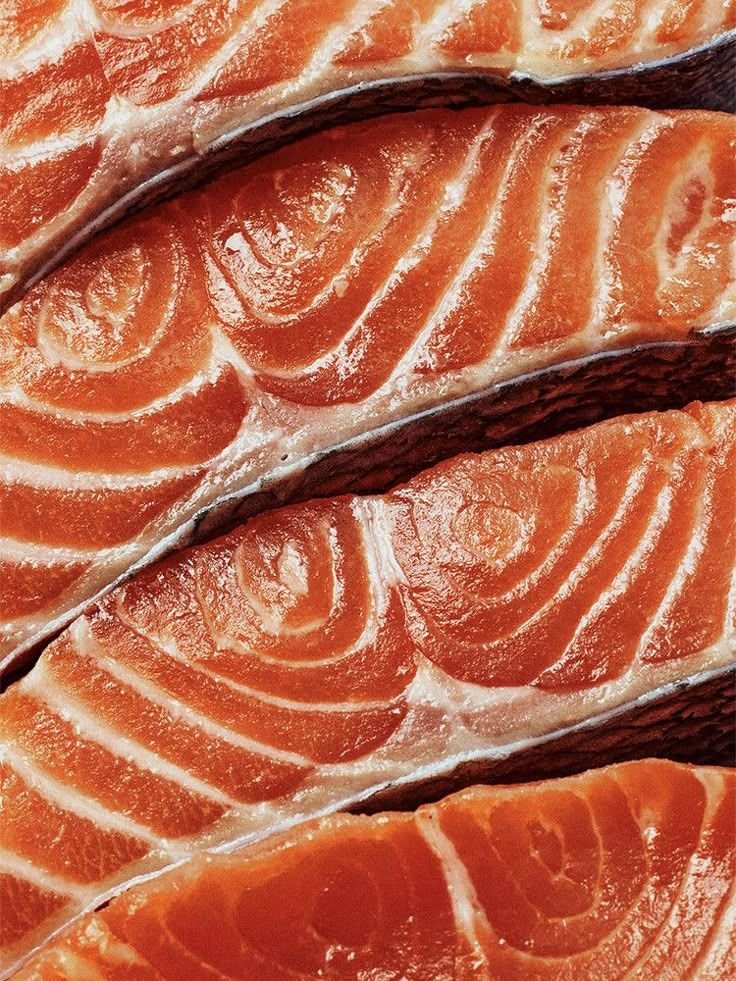 Close-up of fresh salmon fillets with orange-pink flesh and white marbling.