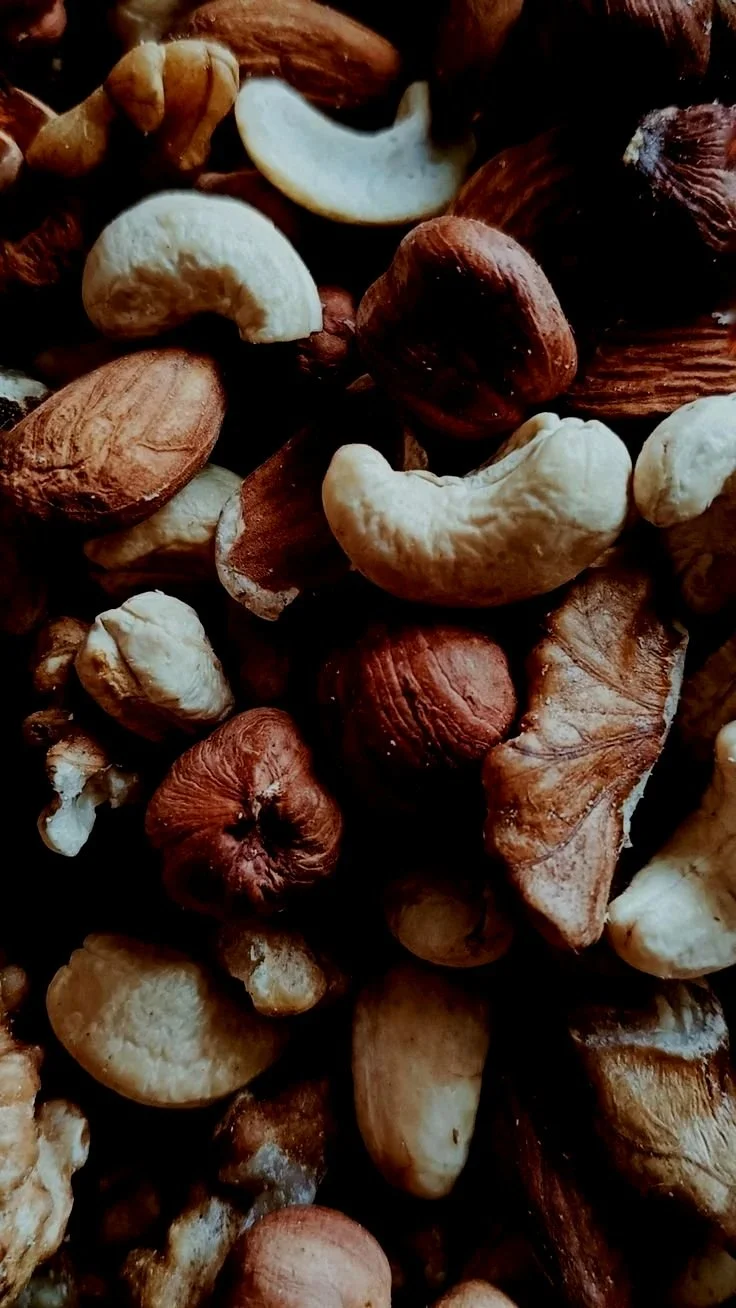 A close-up of a mixture of cashew nuts, almonds, and hazelnuts.