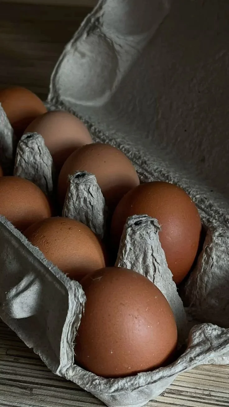 Brown eggs in a cardboard egg carton on a wooden surface.