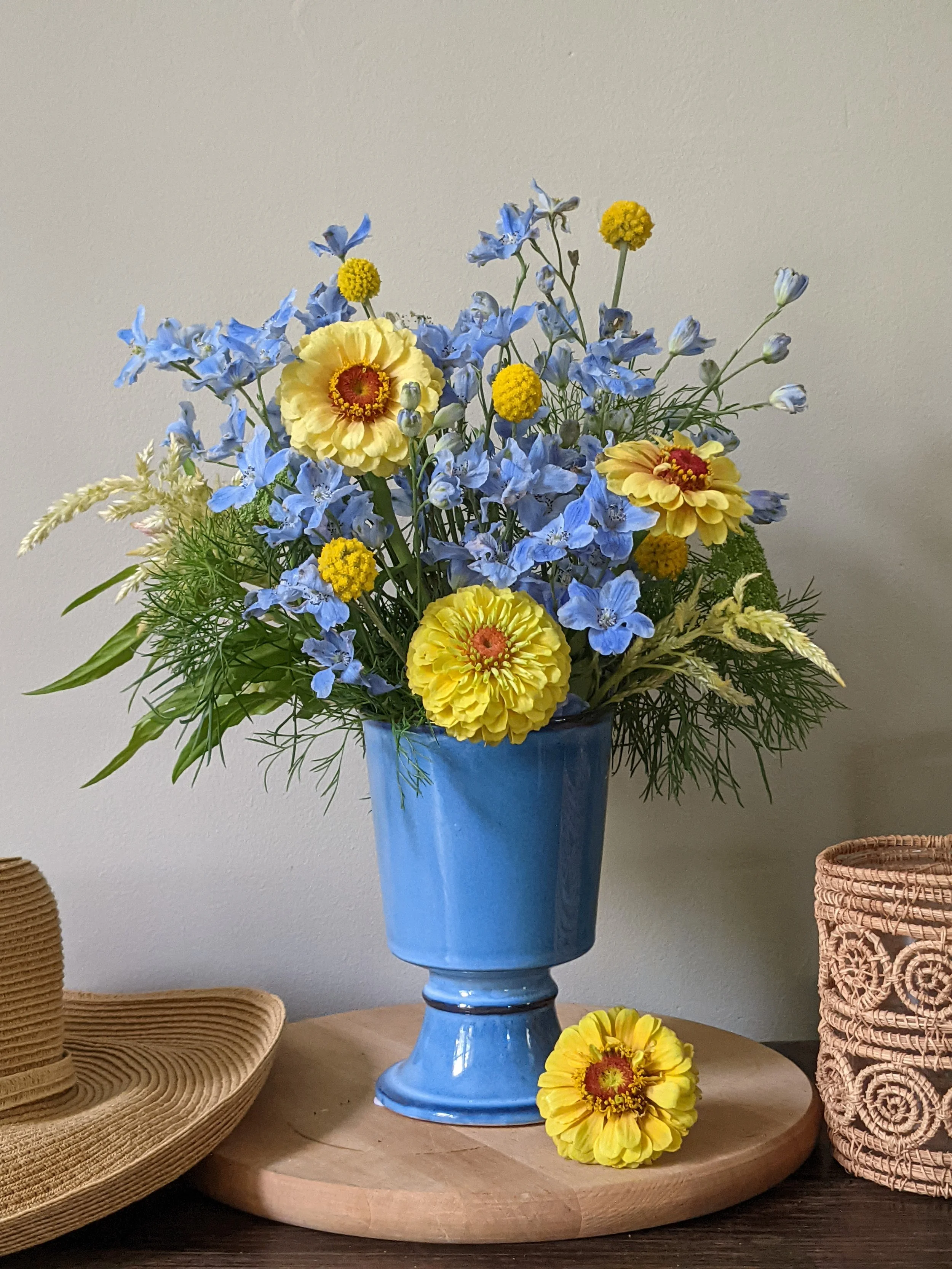 Zinnia Peach Mix_mixed bouq with Breezin Delphs pale blue, Celosia Shimmer Mix, Craspedia (gold) & Ammi_in small blue pedestal vase_vert.jpg