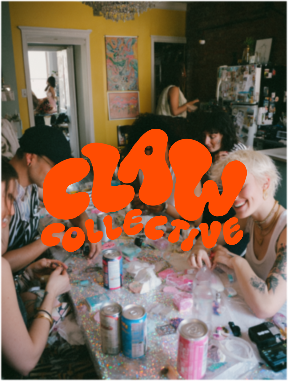People gathered around a table covered with colorful items, with a yellow wall and artwork in the background, and a person visible through an open door in the distance.