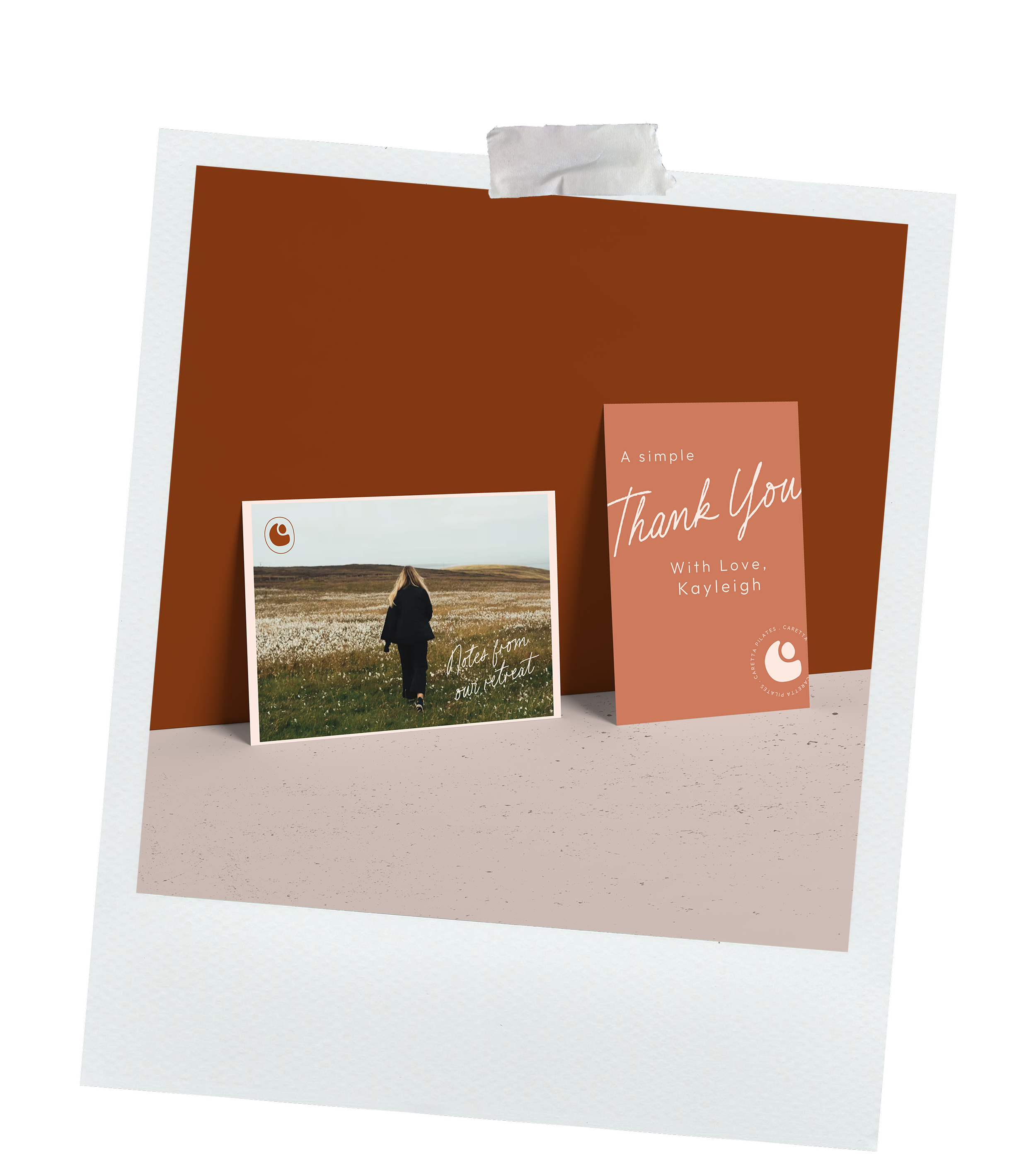 A thank you card with a pink background and handwritten style text that says "Thank You". It is attached to a brown background with a white border, taped at the top with a piece of white tape. There is also a photograph showing a person walking on a grassy landscape under a cloudy sky.