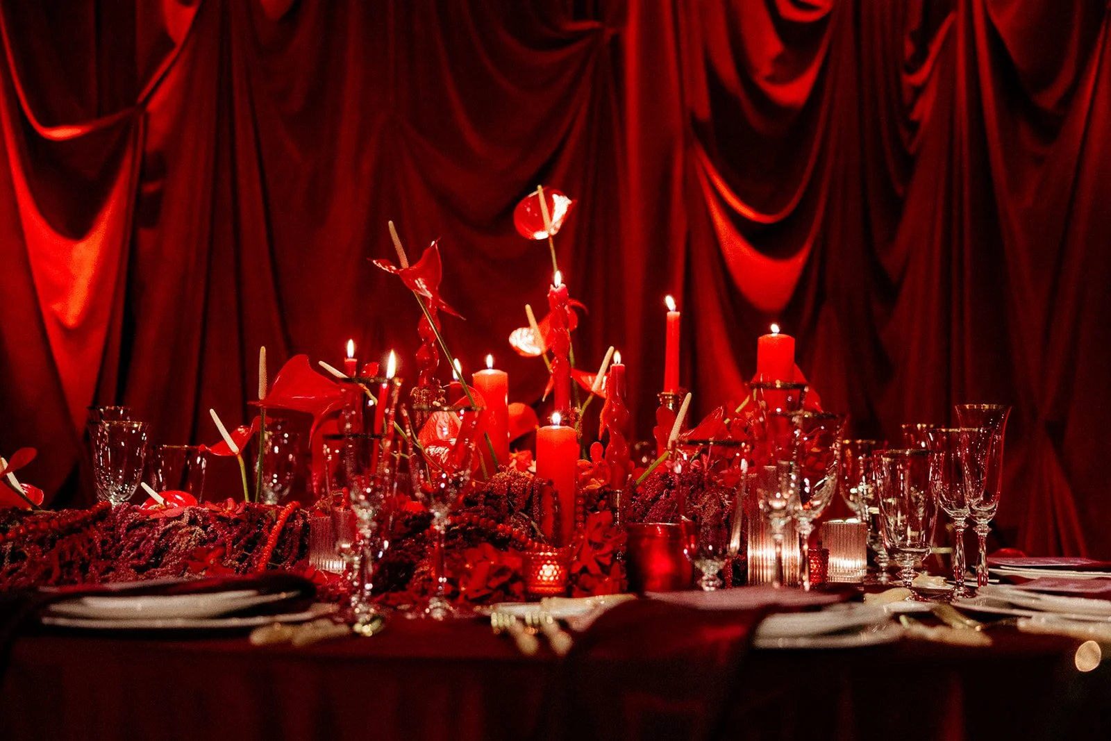 Red velvet drapes and a candlelit red tablescape with anthurium centerpieces