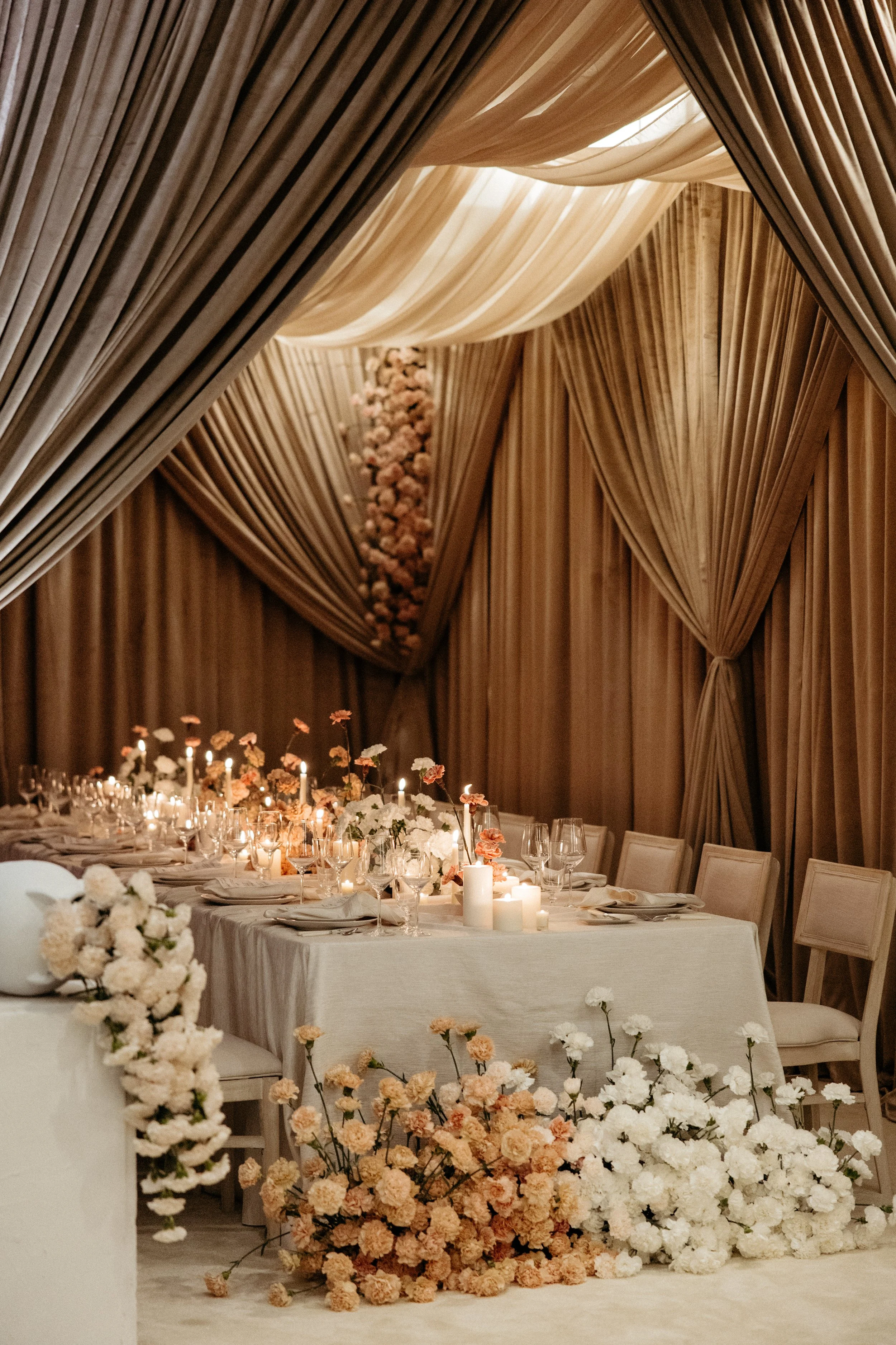 Draped champagne ballroom with a candlelit table and blush florals at a Pittsburgh wedding