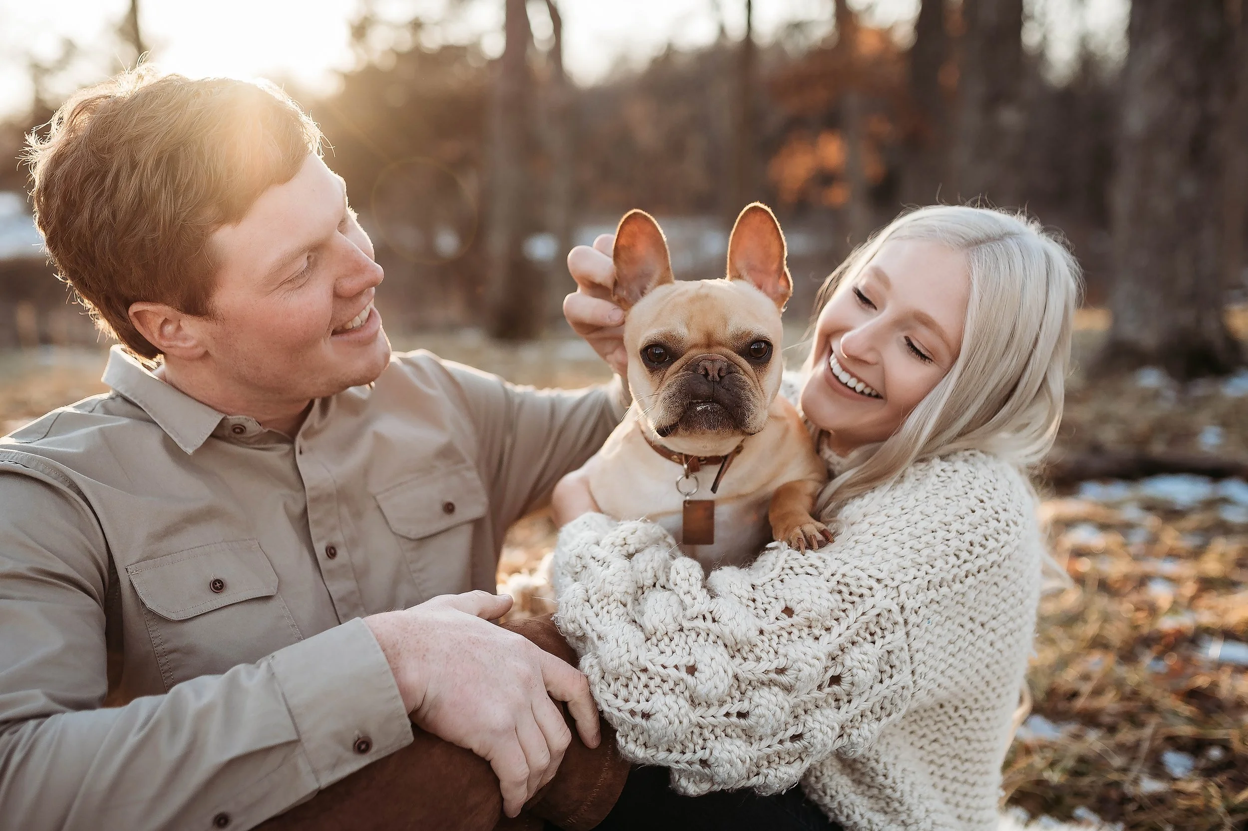 Lauren and her husband Eric holding their French bulldog in an autumn field