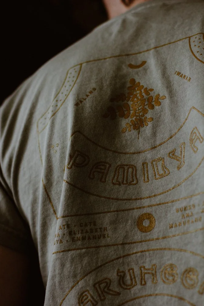 Close-up of a beige t-shirt with yellow printed designs, including decorative elements.