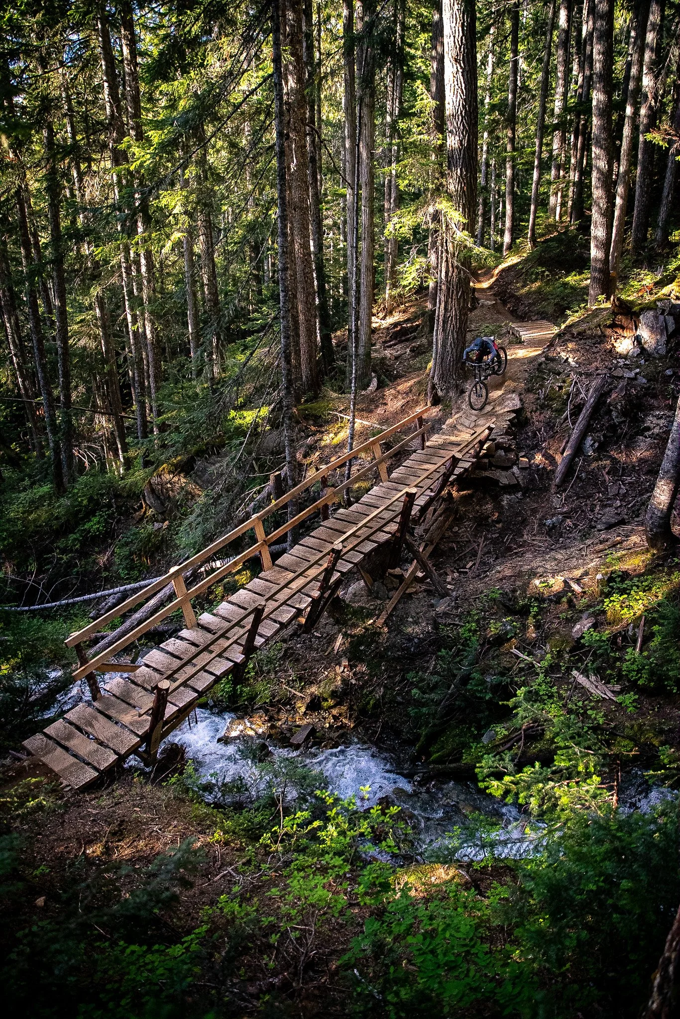 A serene landscape featuring a lake surrounded by rolling hills and tall mountains in the background. The sky is overcast with clouds.