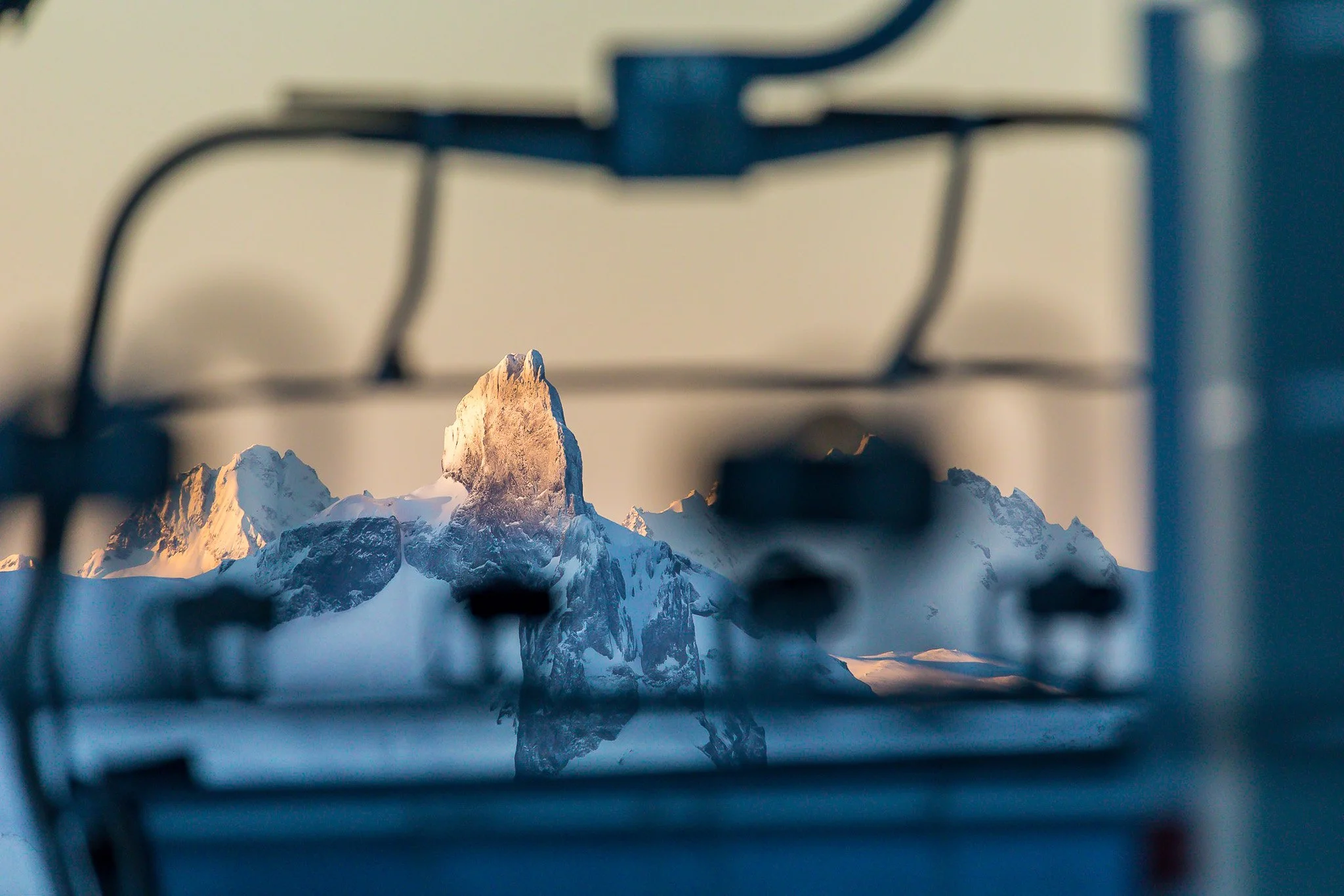 Snow-capped mountain peak seen through a blurred stove grate in the foreground.