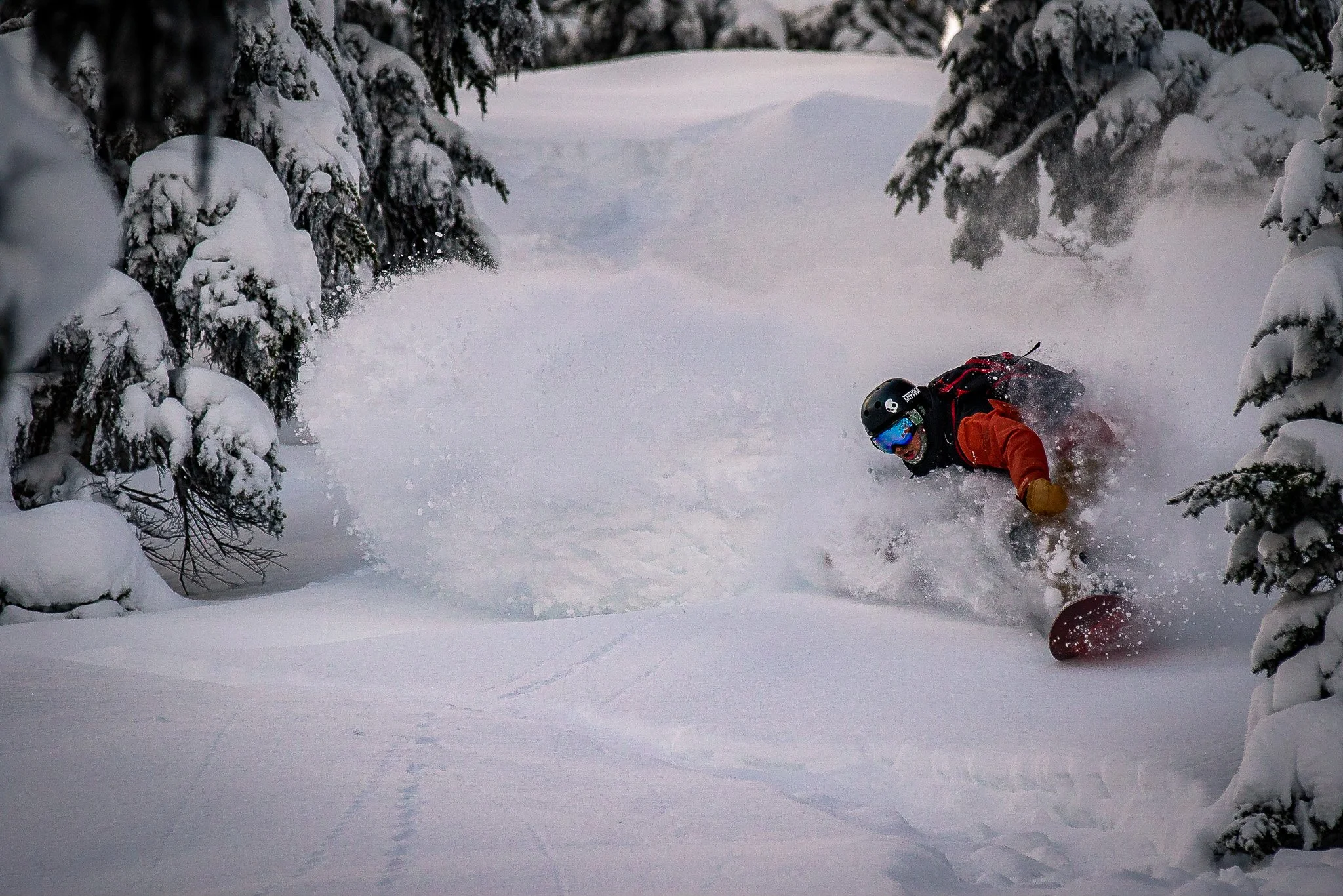 Mountain range with snow-capped peaks in the background and a small modern building on a green hillside in the foreground.