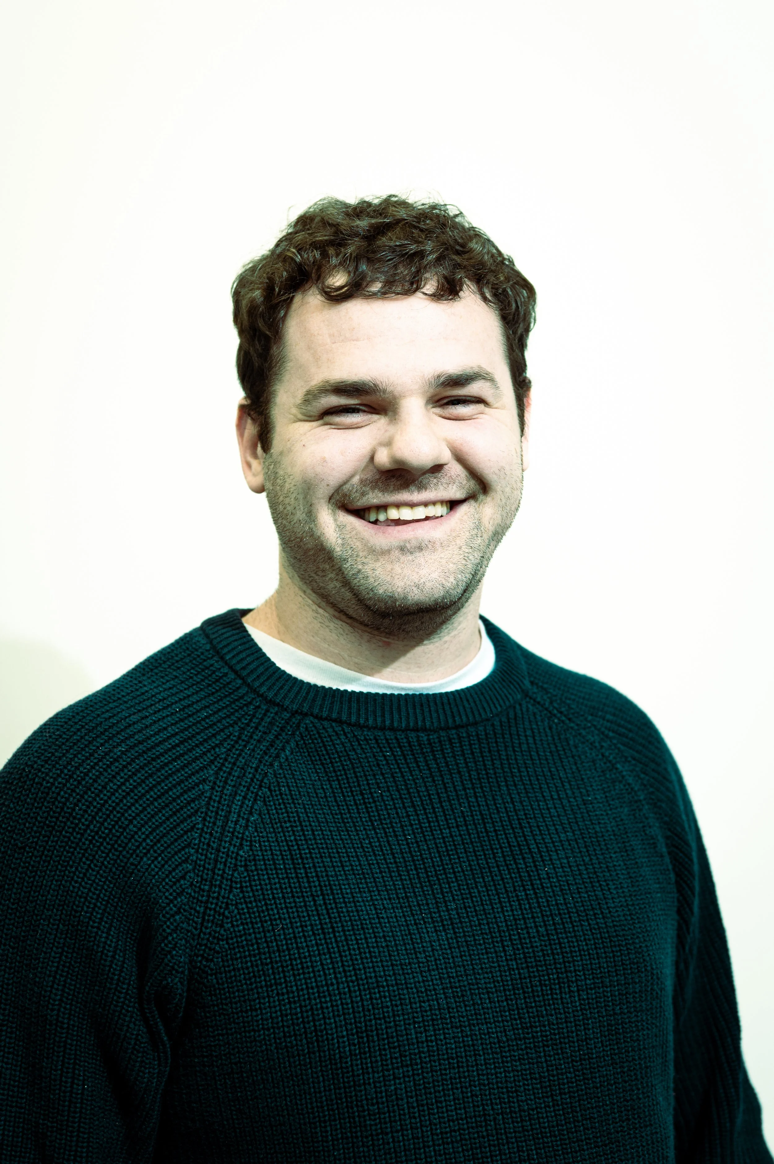 Man with dark sweater, smiling.