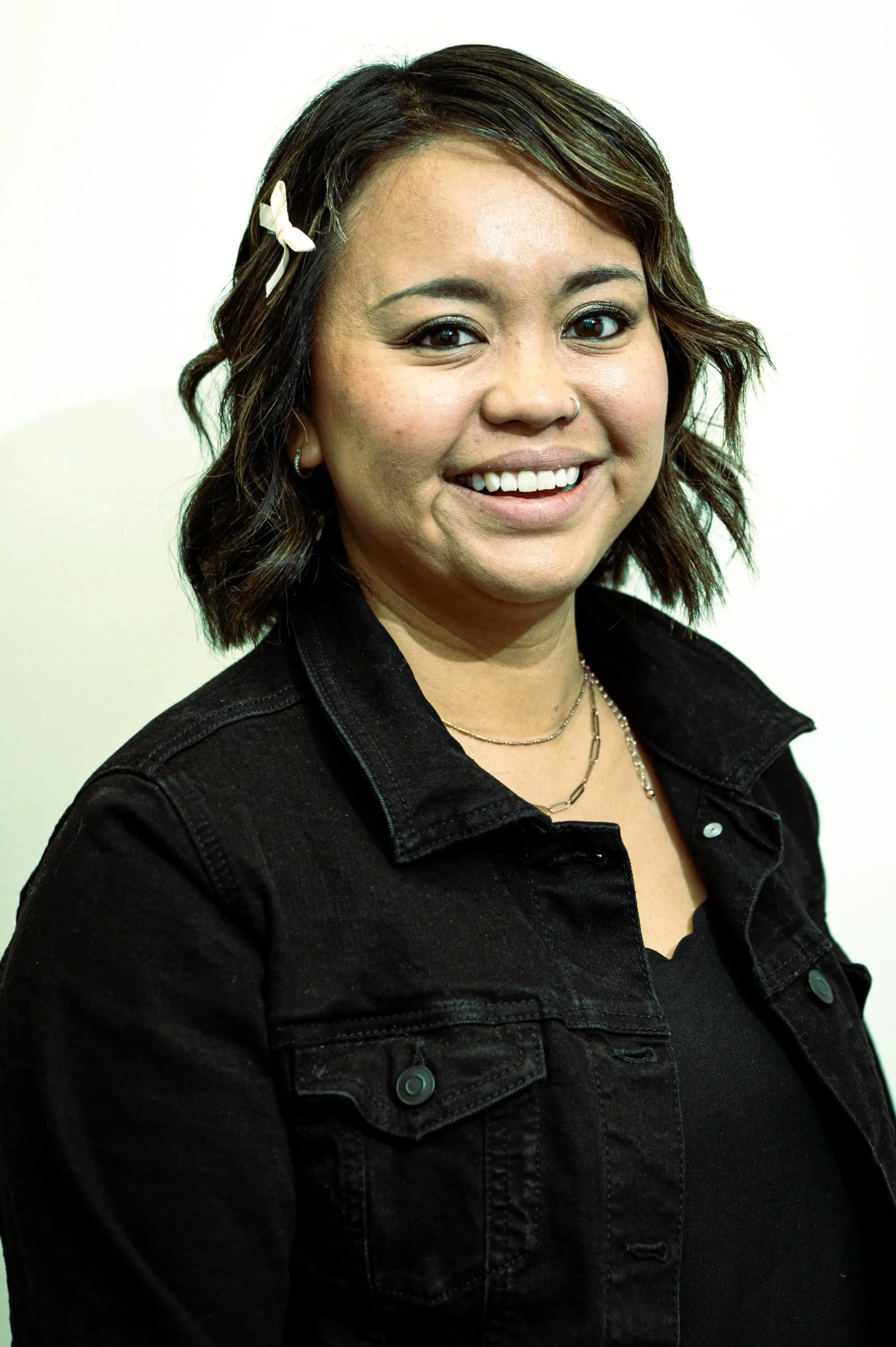 Woman with short wavy hair and hairbow, smiling.