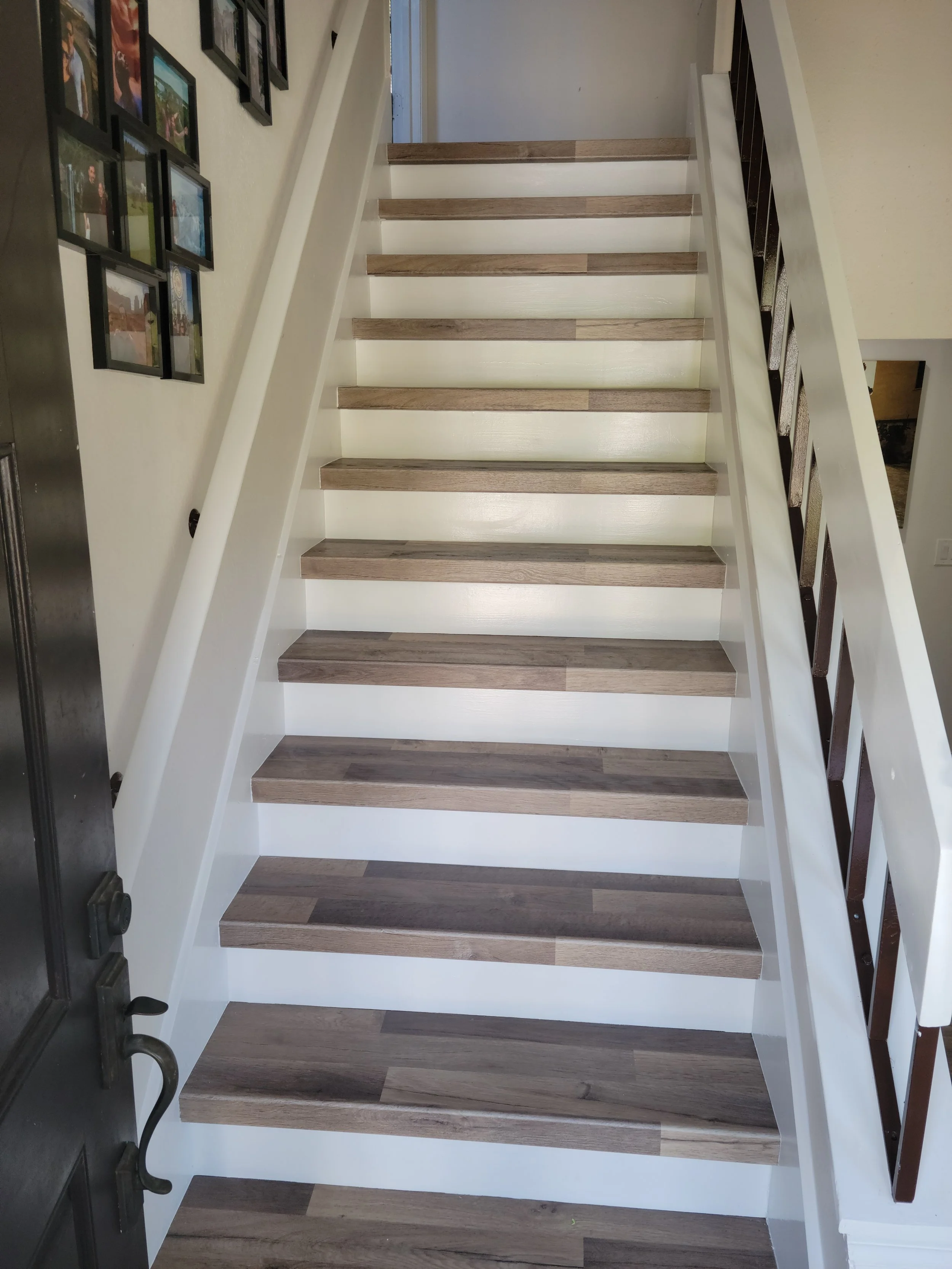 Wooden staircase with white risers and dark brown handrails on each side, inside a home.