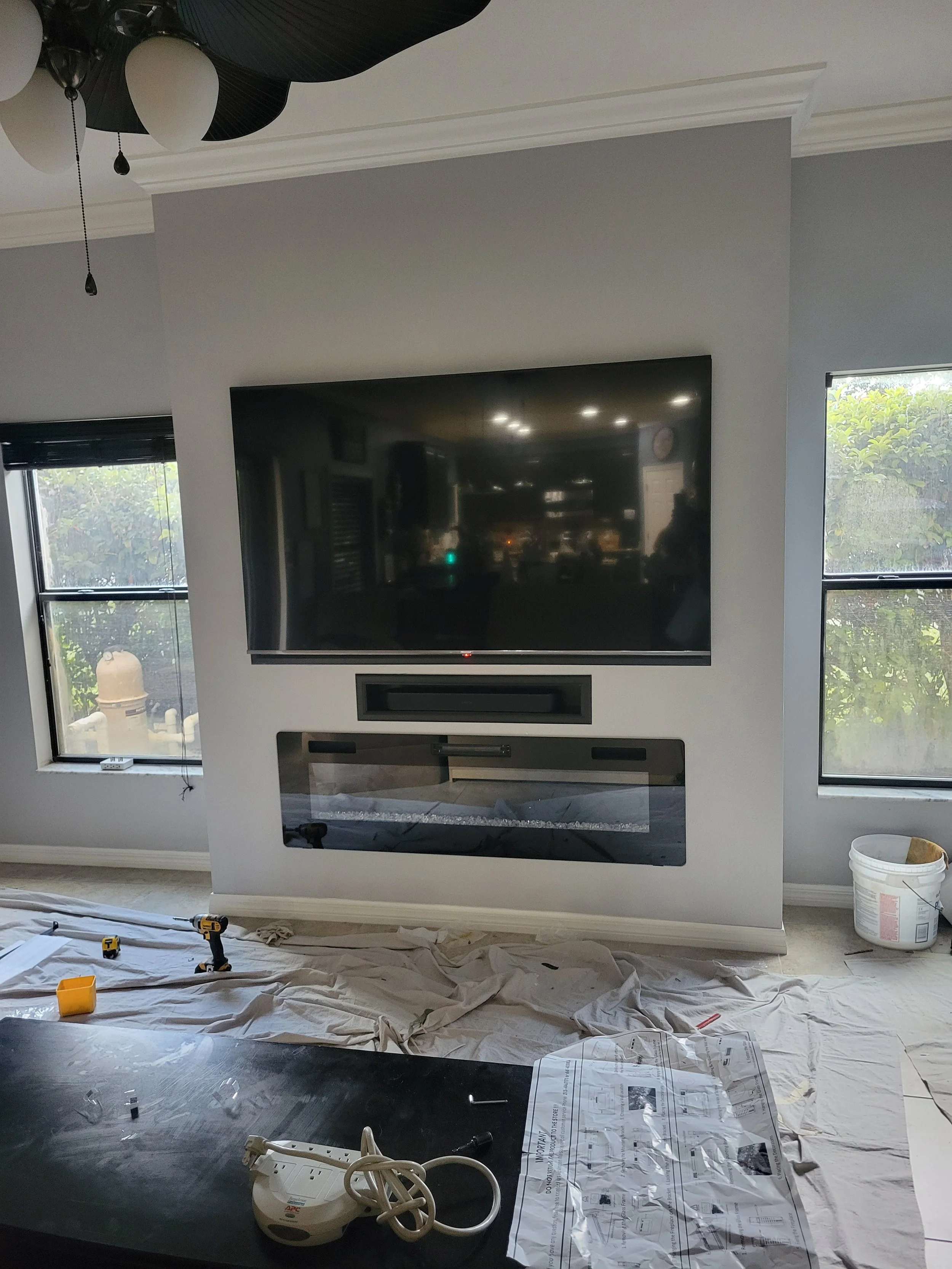 Living room wall with a mounted flat-screen TV, fireplace below.