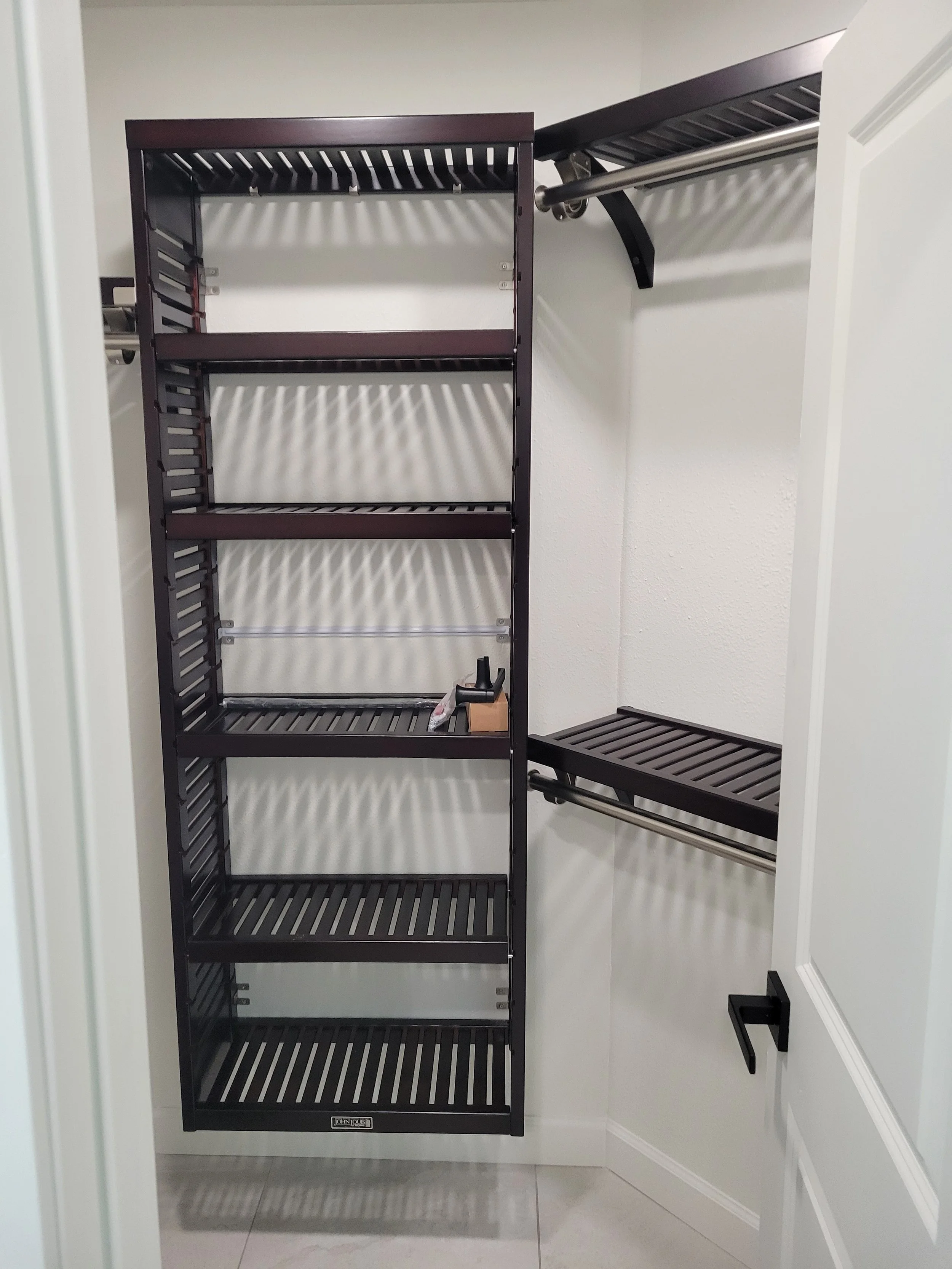 Empty closet with black metal shelving and rods for hanging clothes.