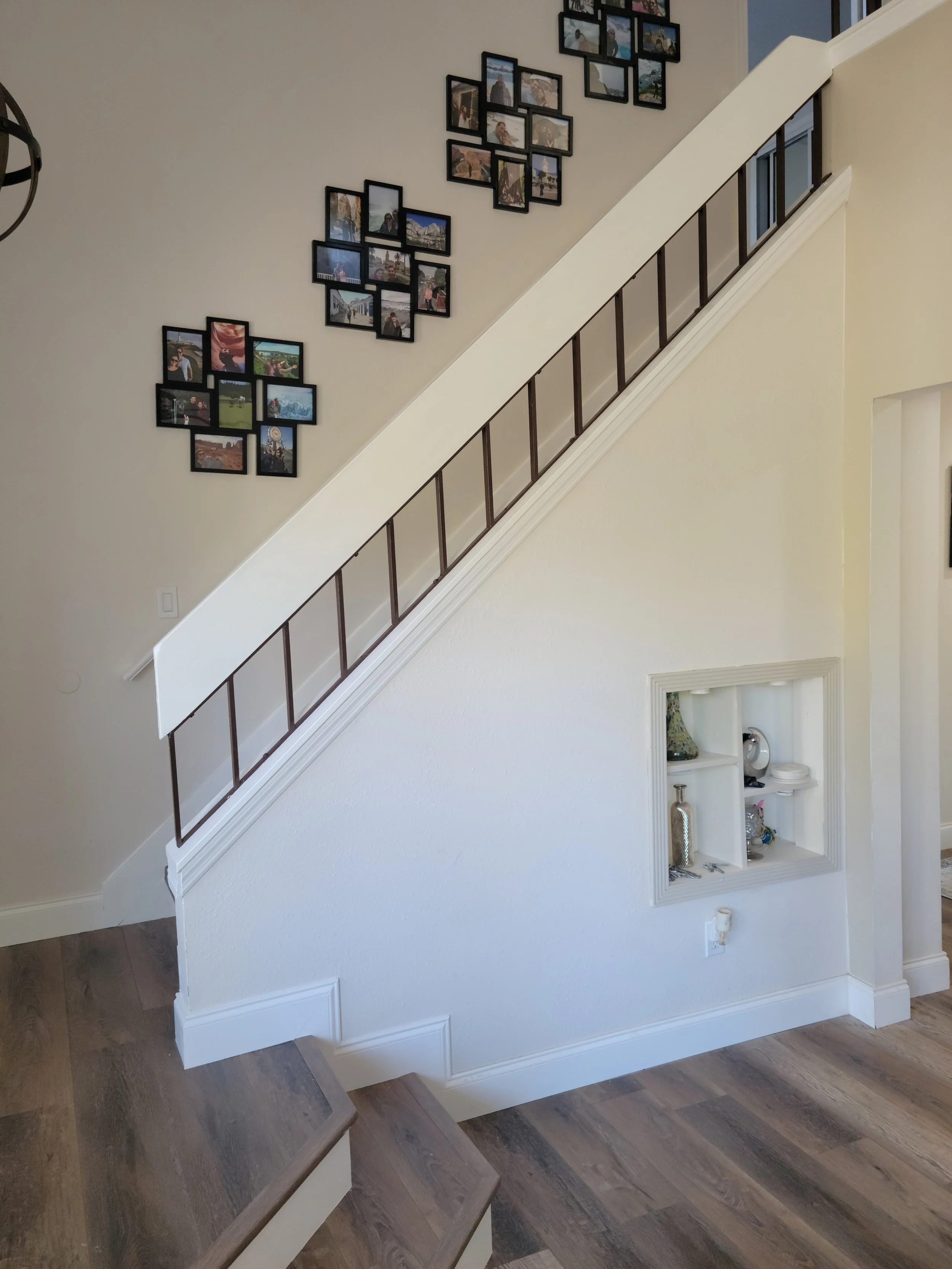 Interior of a home with a staircase, photo collage on the wall, and decorative built-in shelves on the lower wall.