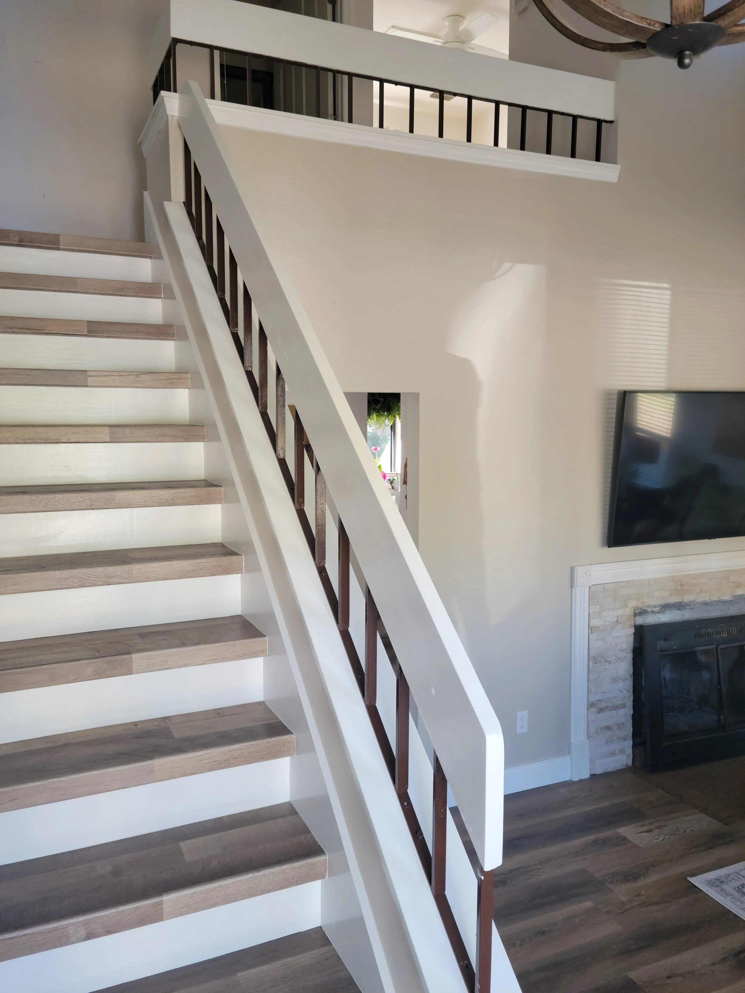 Interior view of a modern home staircase leading to an upper floor with a black railing.