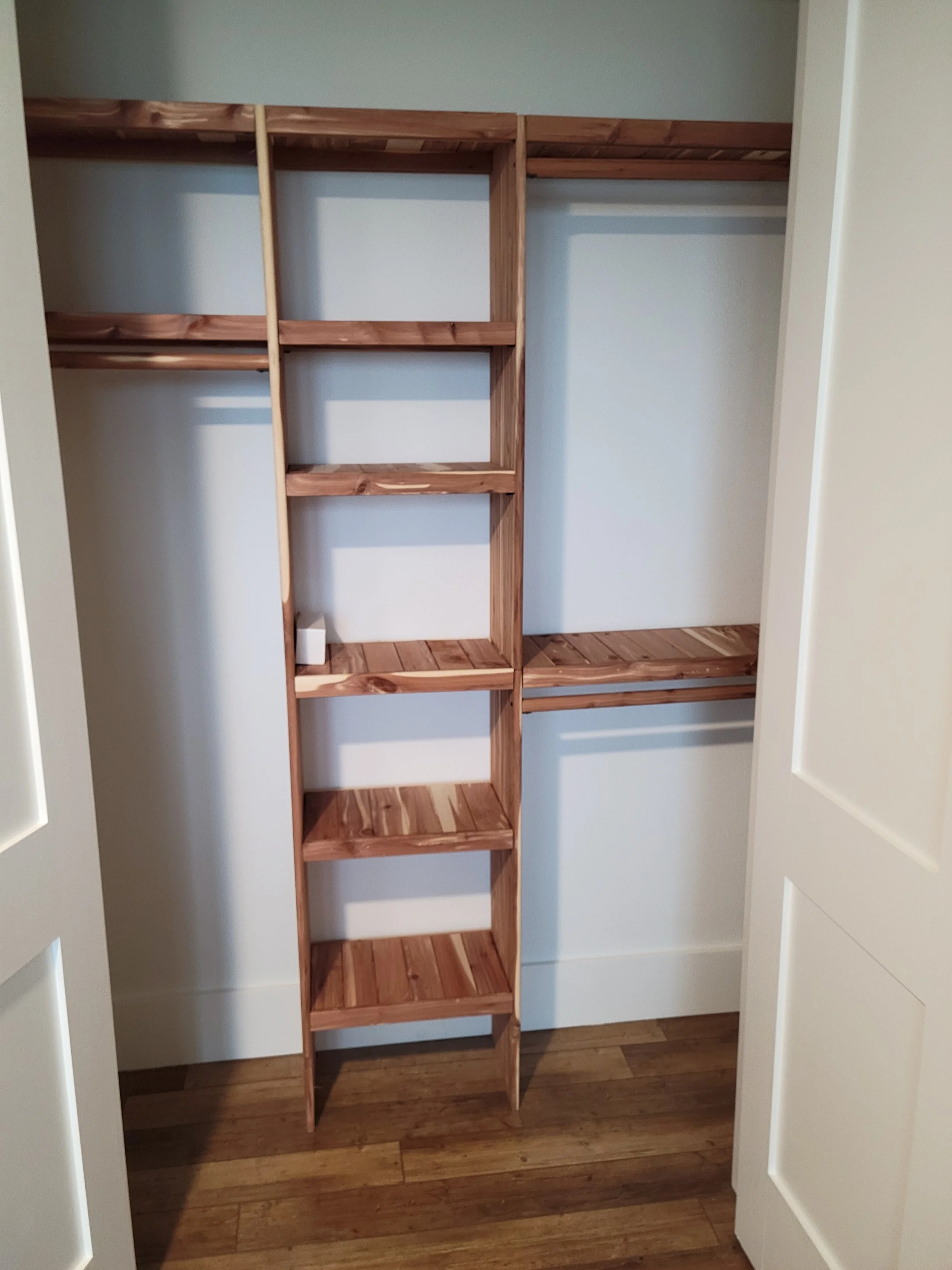 Empty closet with wooden shelving and hanging rods.