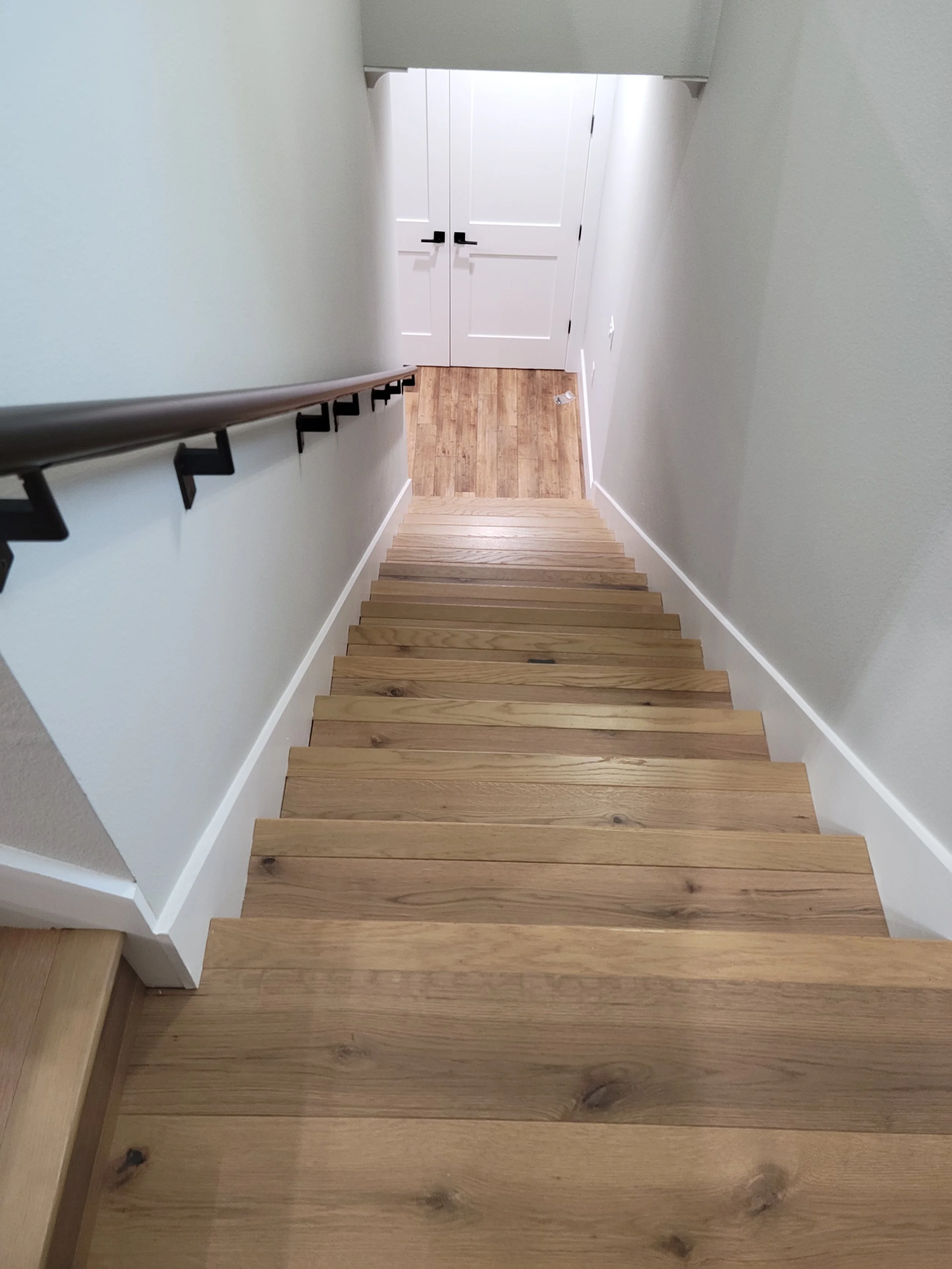 Top view of wooden staircase leading down to a landing with closed white double doors.