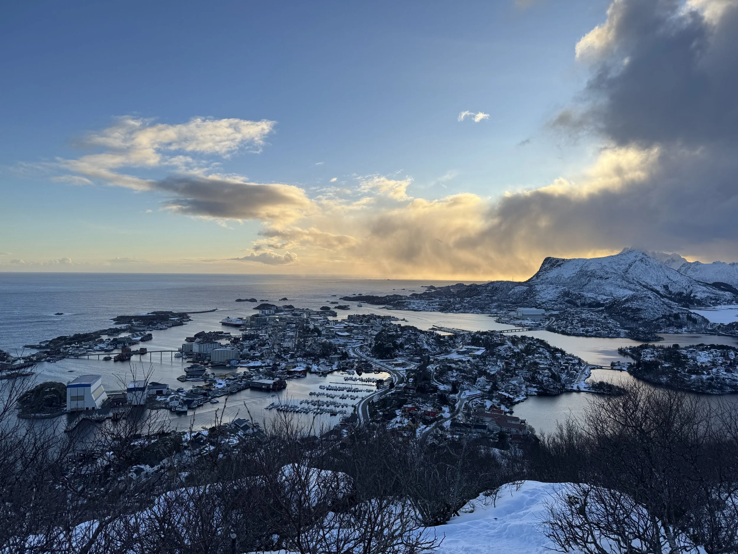 Coastal town with snowy mountains and ocean at sunset