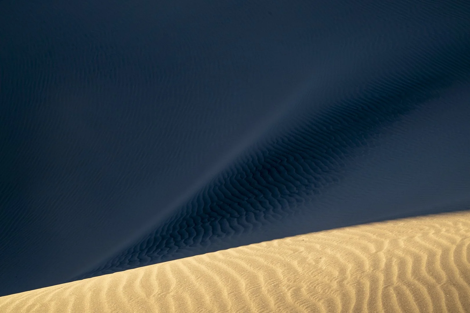 Mesquite Dunes - as the sun begins to set, some dunes are still lit by its warm light as others are in deep blue shadow.